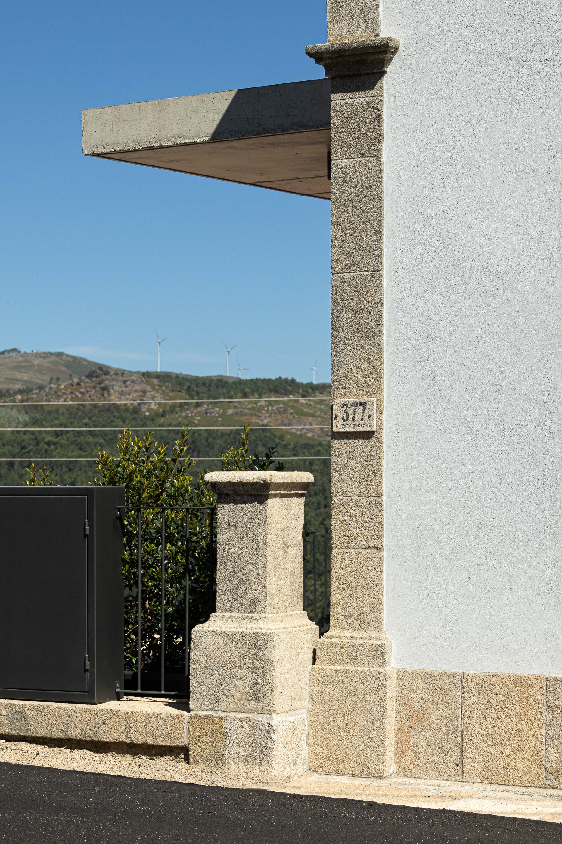 Fachada: Pormenor da fachada com número 377, cantaria em granito e vedação metálica preta. — Casa Arco arquitetura Tiago Sousa Arquitecto em Paredes de Coura