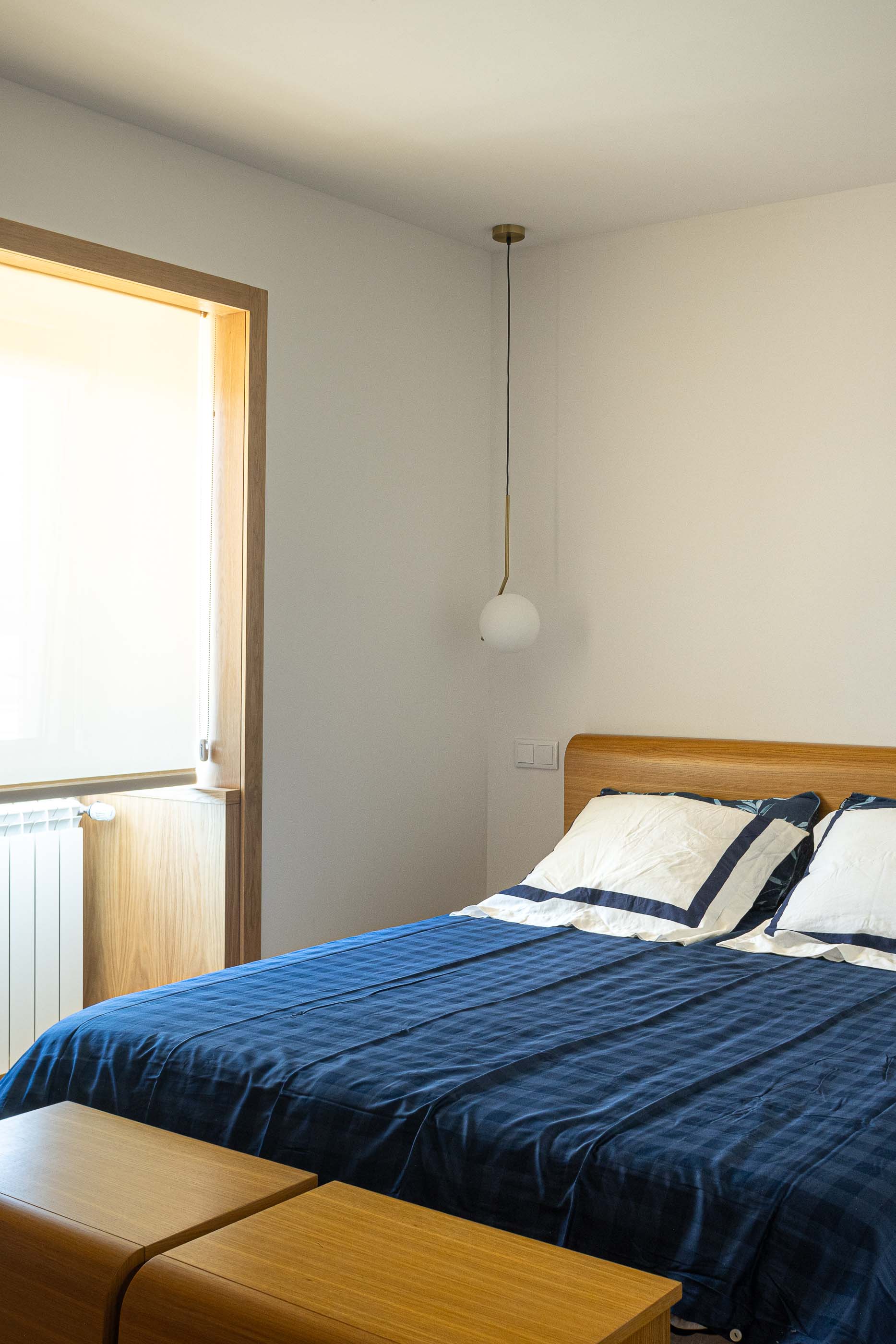 Quarto: Pormenor da cama de casal com cabeceira em madeira e roupa de cama azul. — Casa Arco arquitetura Tiago Sousa Arquitecto em Paredes de Coura