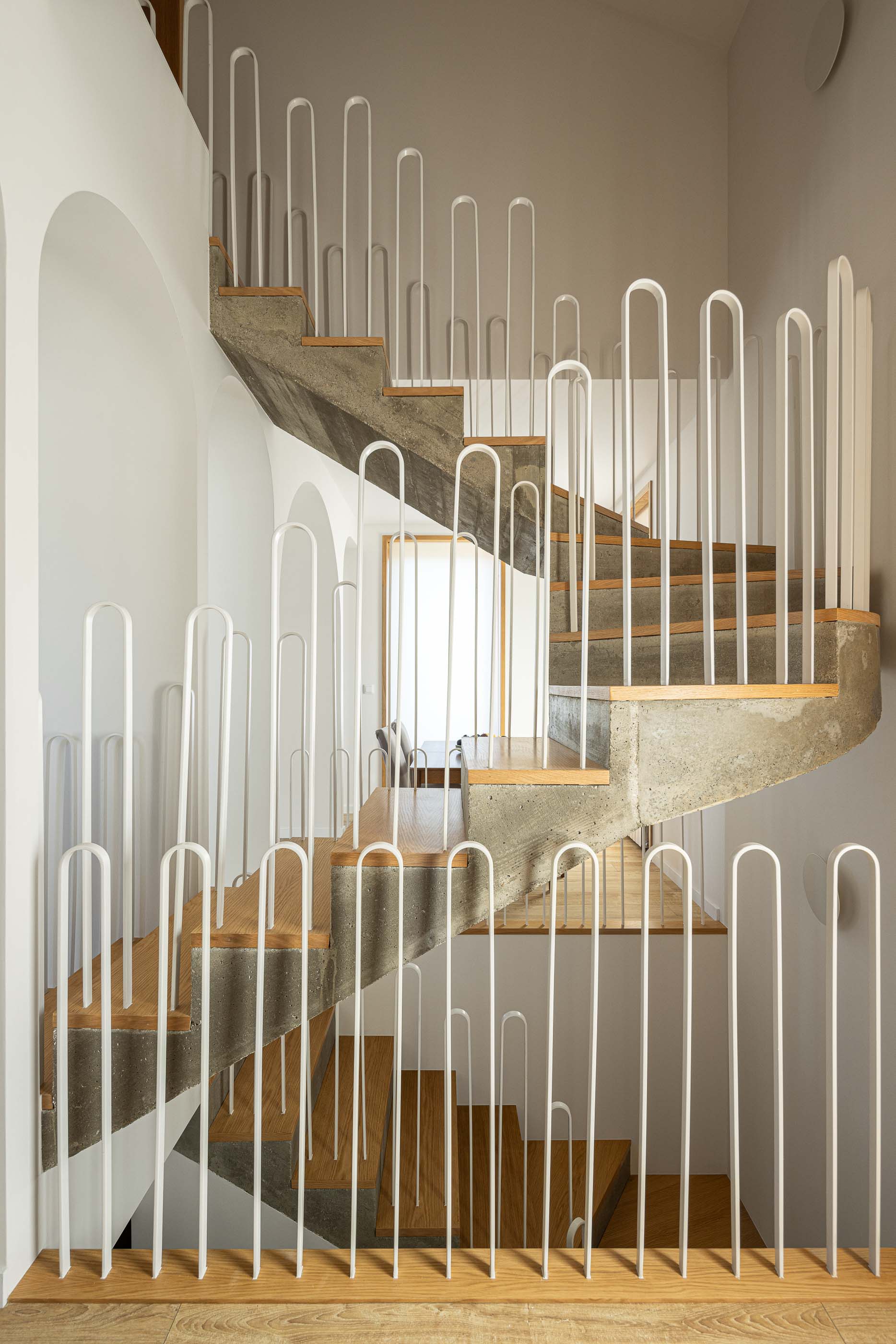 Escada: Vista da escada em betão e madeira com guarda em metal branco. — Casa Arco arquitetura Tiago Sousa Arquitecto em Paredes de Coura