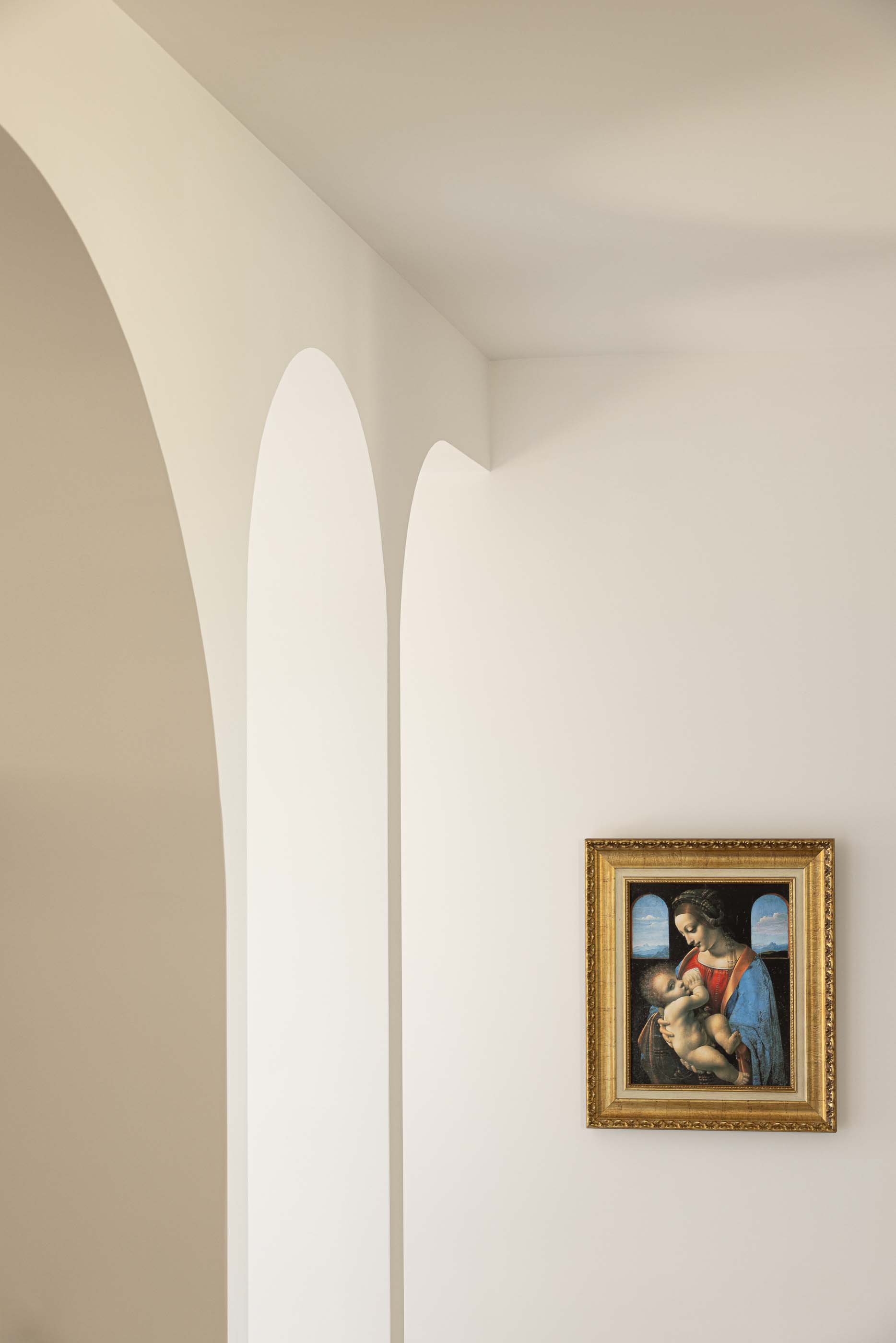 Hall: Detalhe de um quadro com moldura dourada numa parede branca com arcos. — Casa Arco arquitetura Tiago Sousa Arquitecto em Paredes de Coura