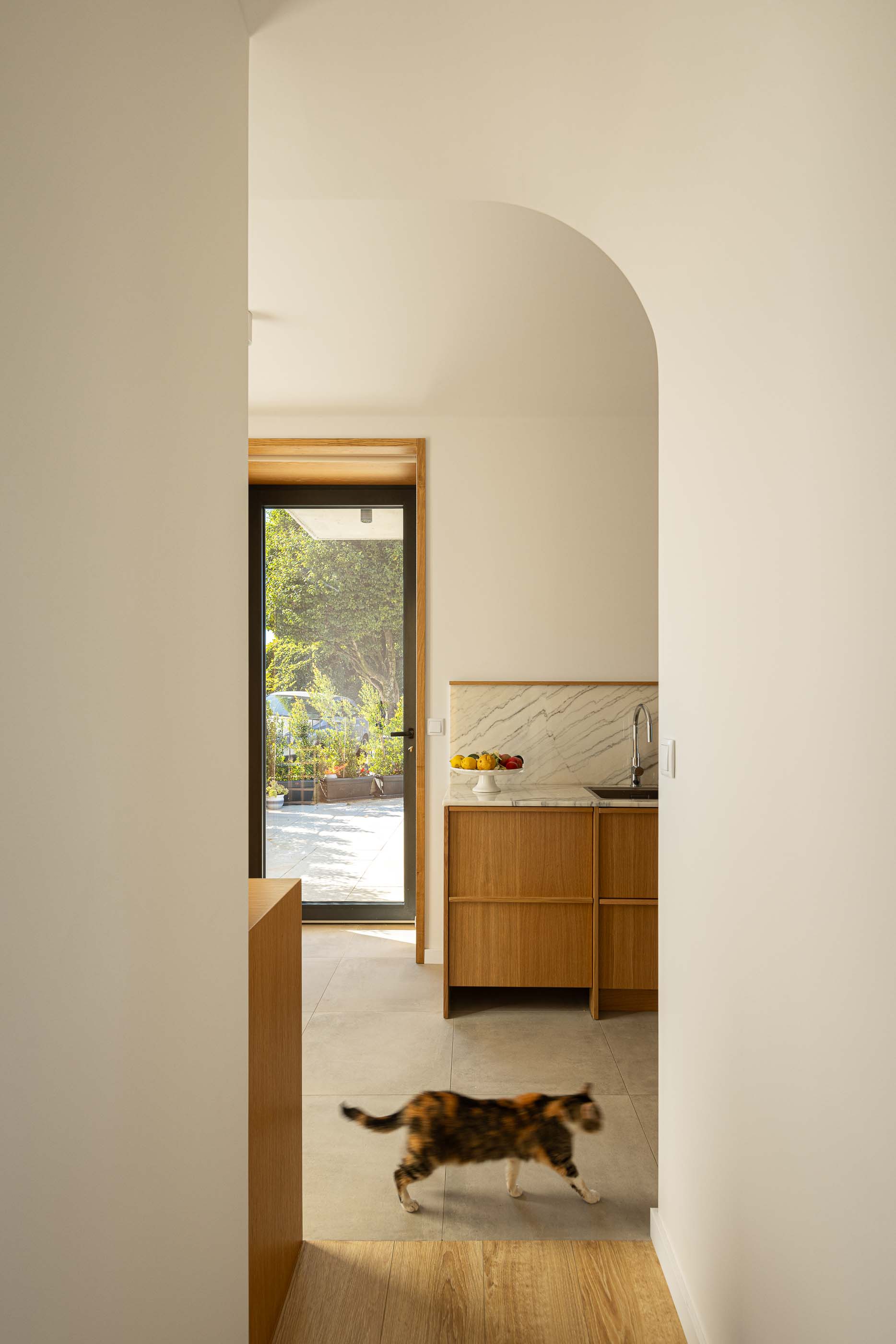 Cozinha: Vista da cozinha com armários em madeira e acesso ao exterior. — Casa Arco arquitetura Tiago Sousa Arquitecto em Paredes de Coura