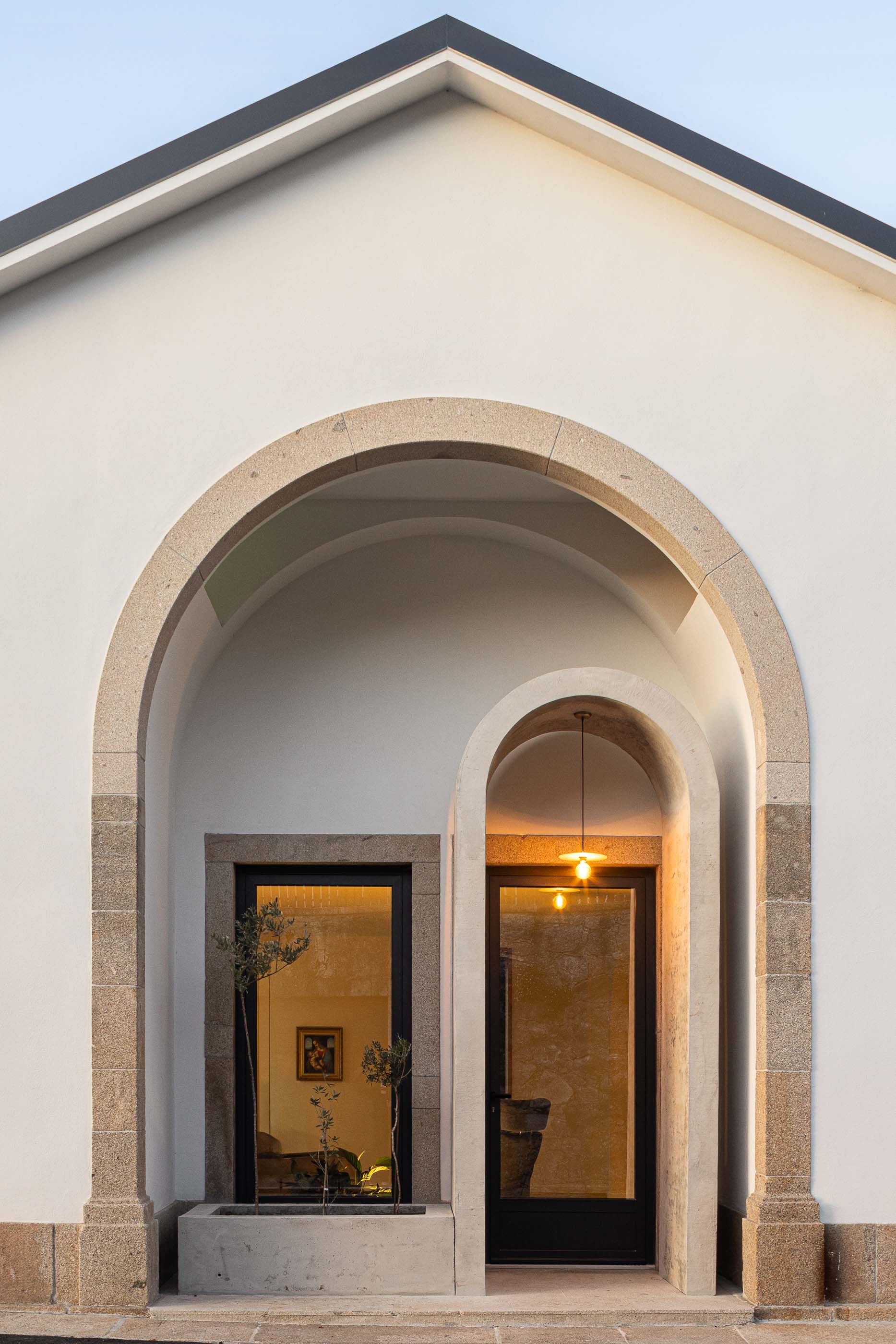 Fachada: Detalhe da fachada principal com arcos em pedra e portas envidraçadas. — Casa Arco arquitetura Tiago Sousa Arquitecto em Paredes de Coura