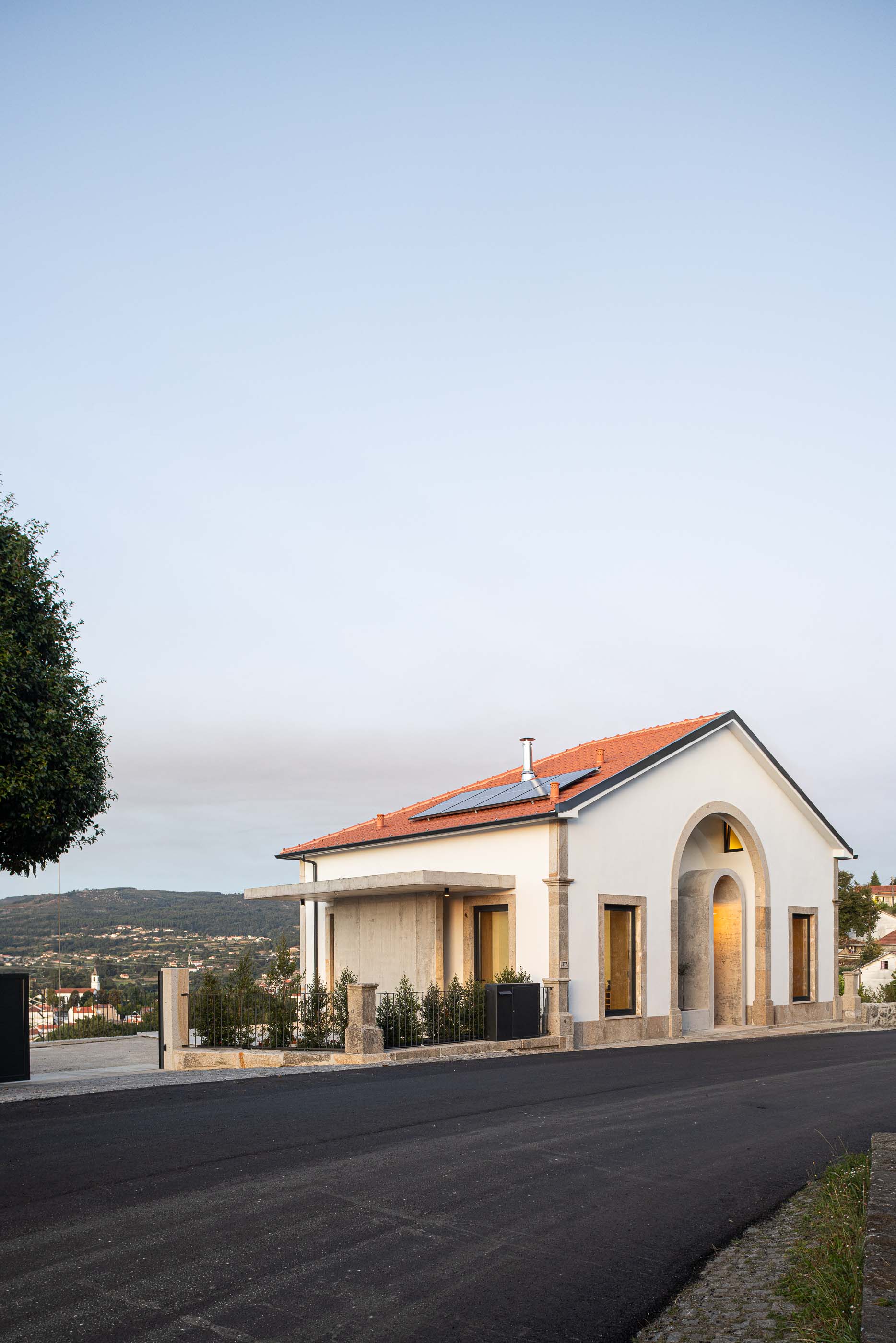 Exterior: Vista geral da casa com telhado de telha e cantaria em granito. — Casa Arco arquitetura Tiago Sousa Arquitecto em Paredes de Coura