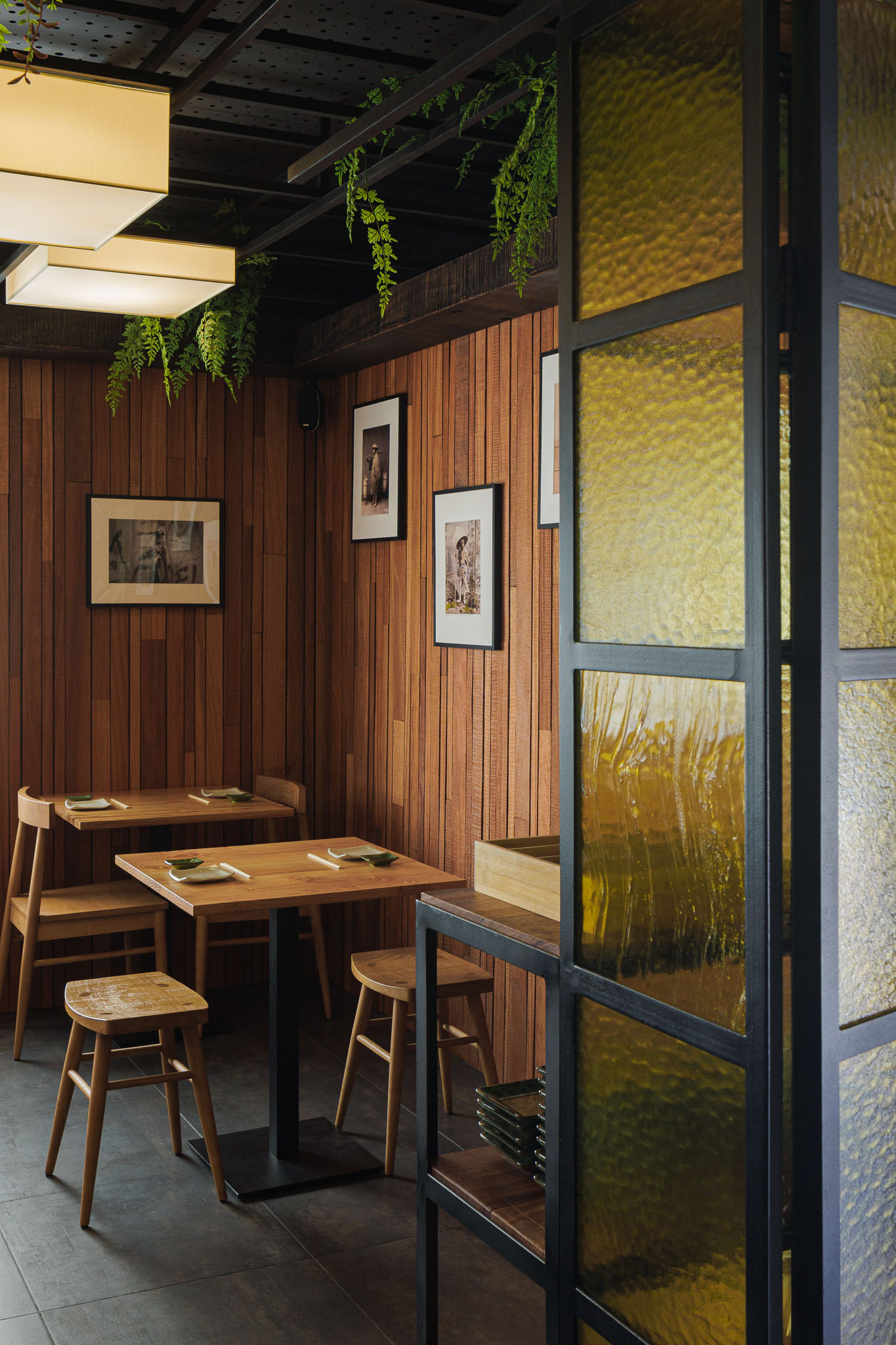 Sala de refeições: Mesas e cadeiras de madeira, divisória de vidro texturado amarelo em estrutura metálica preta. — Restaurante Izakaya Matsuri arquitetura Ferreira Arquitetos em Aveiro