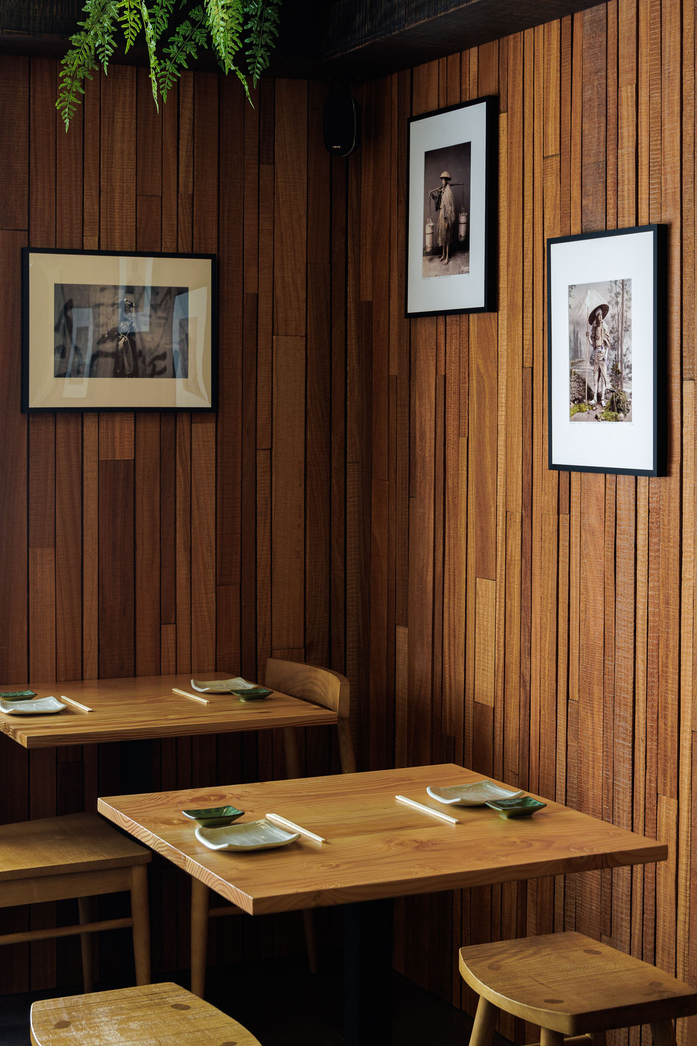Sala de refeições: Paredes revestidas a madeira, mesas e cadeiras de madeira clara, quadros decorativos. — Restaurante Izakaya Matsuri arquitetura Ferreira Arquitetos em Aveiro