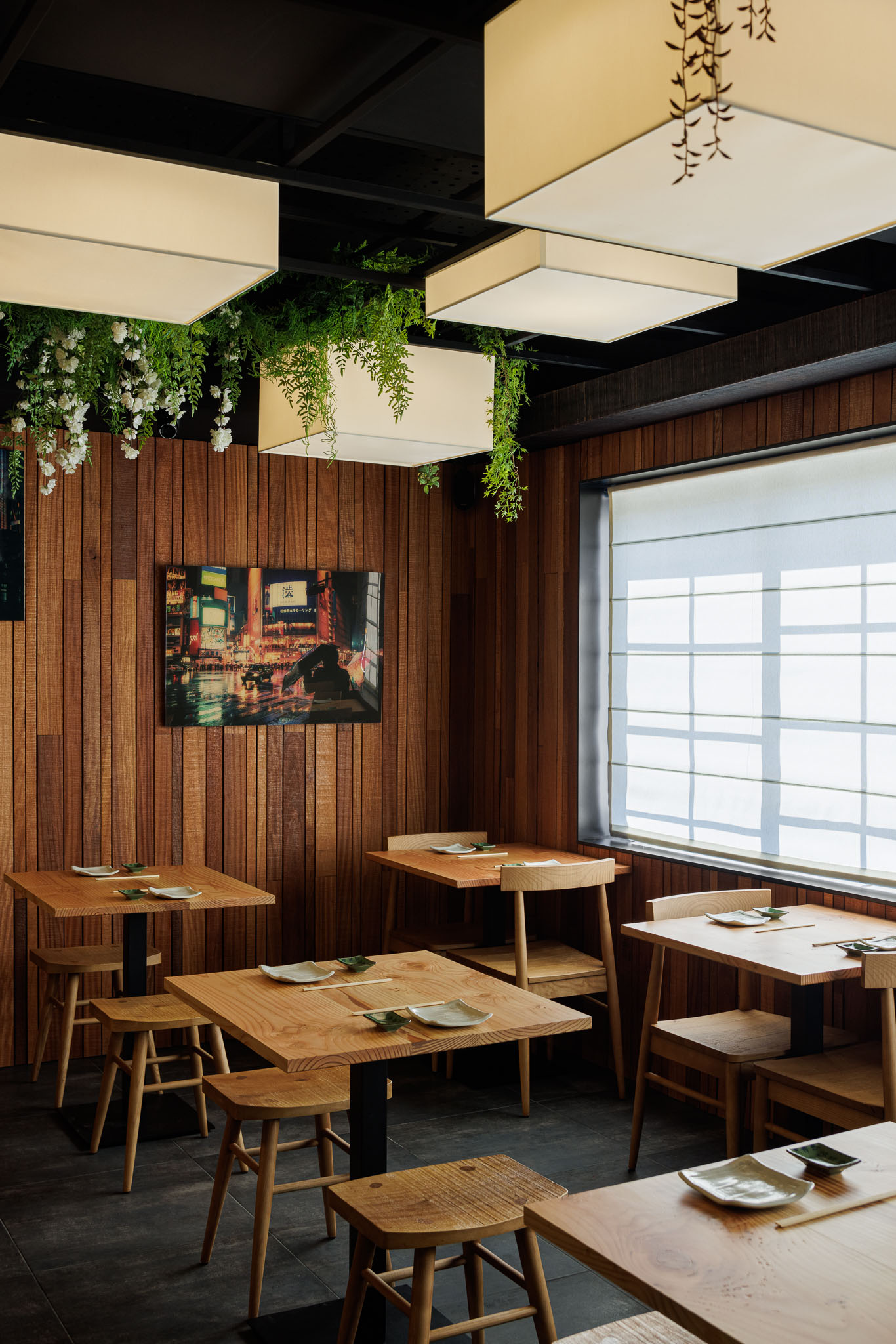 Sala de refeições: Mesas e cadeiras de madeira clara, paredes em madeira, candeeiros quadrados e plantas penduradas. — Restaurante Izakaya Matsuri arquitetura Ferreira Arquitetos em Aveiro