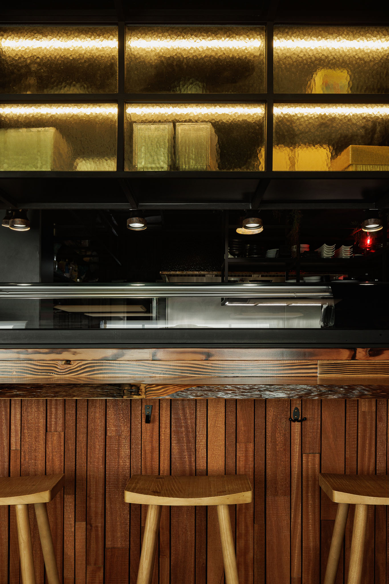 Balcão: Detalhe do balcão em madeira rústica, revestimento em madeira escura e bancos altos de madeira. — Restaurante Izakaya Matsuri arquitetura Ferreira Arquitetos em Aveiro