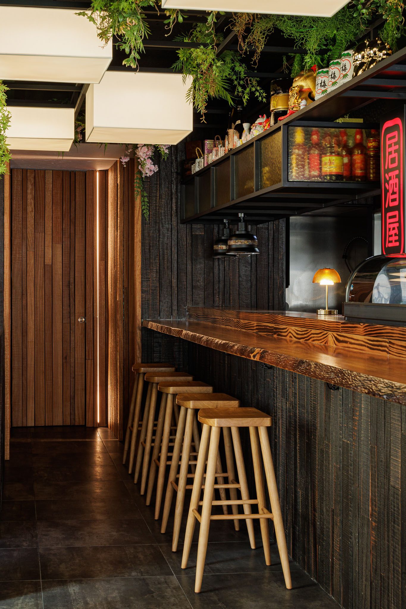 Balcão: Balcão em madeira rústica, bancos altos, porta em madeira com iluminação embutida. — Restaurante Izakaya Matsuri arquitetura Ferreira Arquitetos em Aveiro