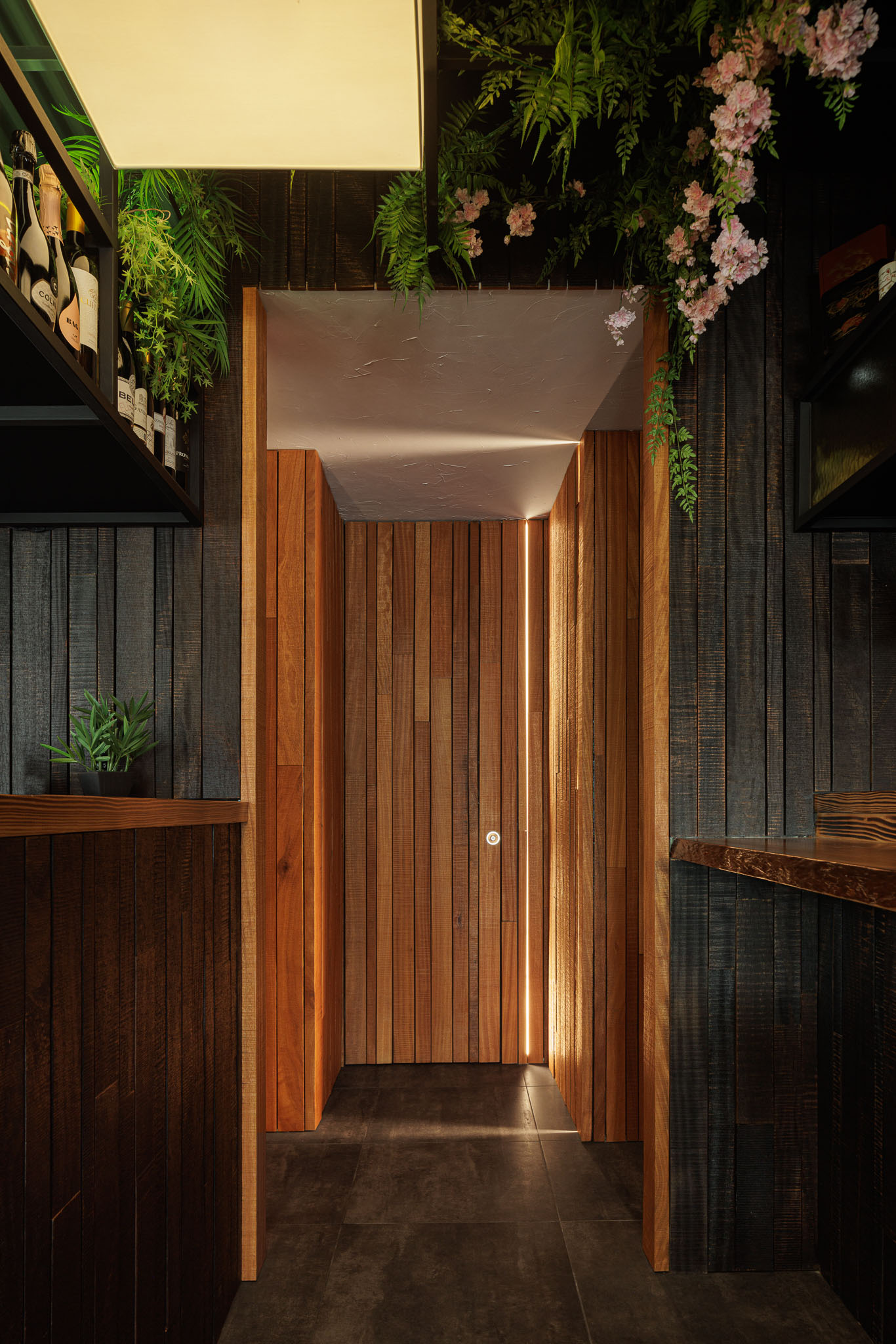 Entrada da casa de banho: Porta em madeira com iluminação embutida, balcão e estantes. — Restaurante Izakaya Matsuri arquitetura Ferreira Arquitetos em Aveiro