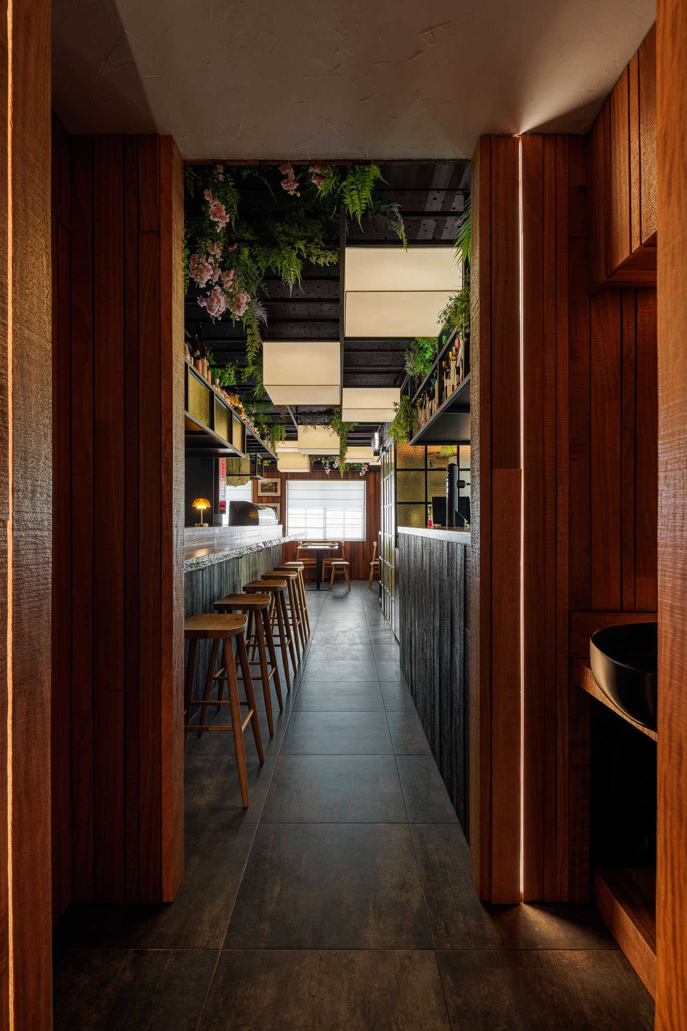 Corredor: Vista do corredor a partir da casa de banho, com balcão, mesas e cadeiras ao fundo. — Restaurante Izakaya Matsuri arquitetura Ferreira Arquitetos em Aveiro