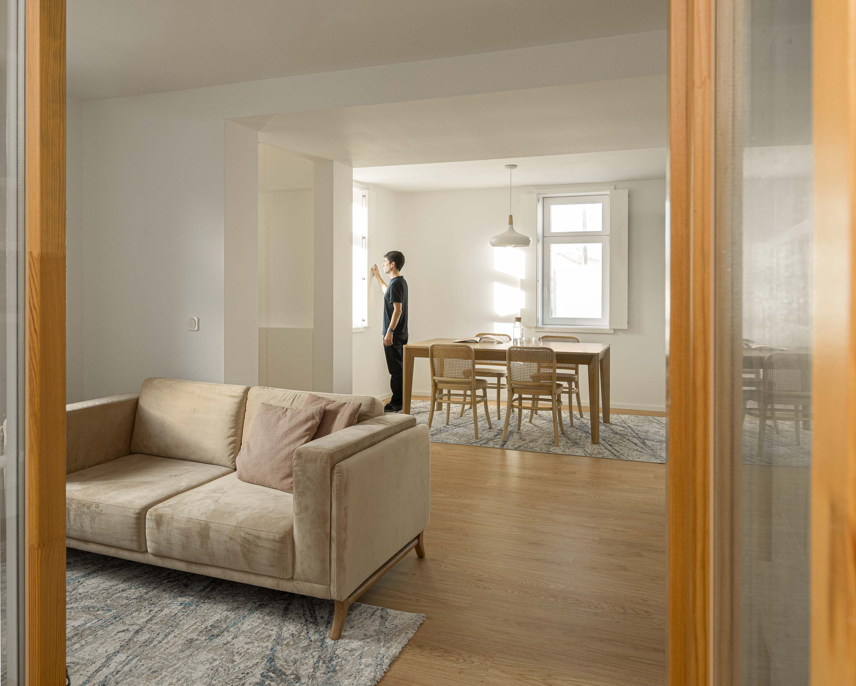 Sala de estar/Jantar: Vista da sala de estar com sofá bege para a sala de jantar com mesa e cadeiras. — Casa Clara arquitetura M2Senos Arquitectos em Ílhavo