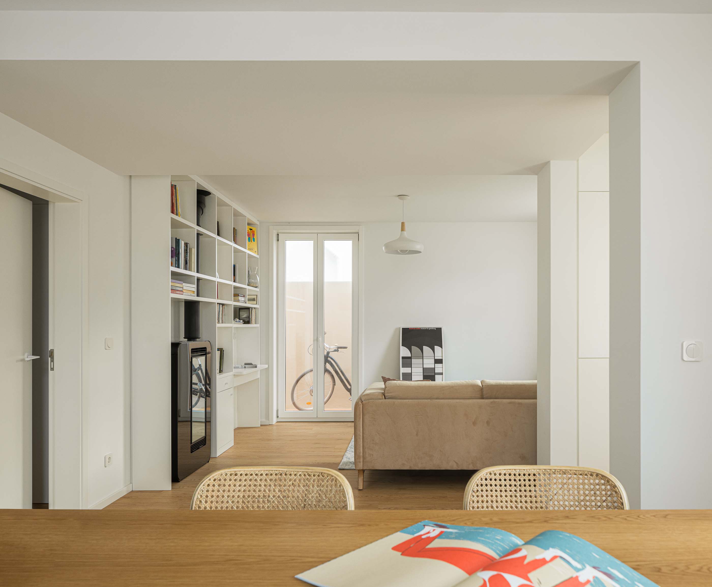 Sala de jantar/Estar/Escritório: Perspectiva da sala de jantar para a sala de estar com estante e escritório. — Casa Clara arquitetura M2Senos Arquitectos em Ílhavo