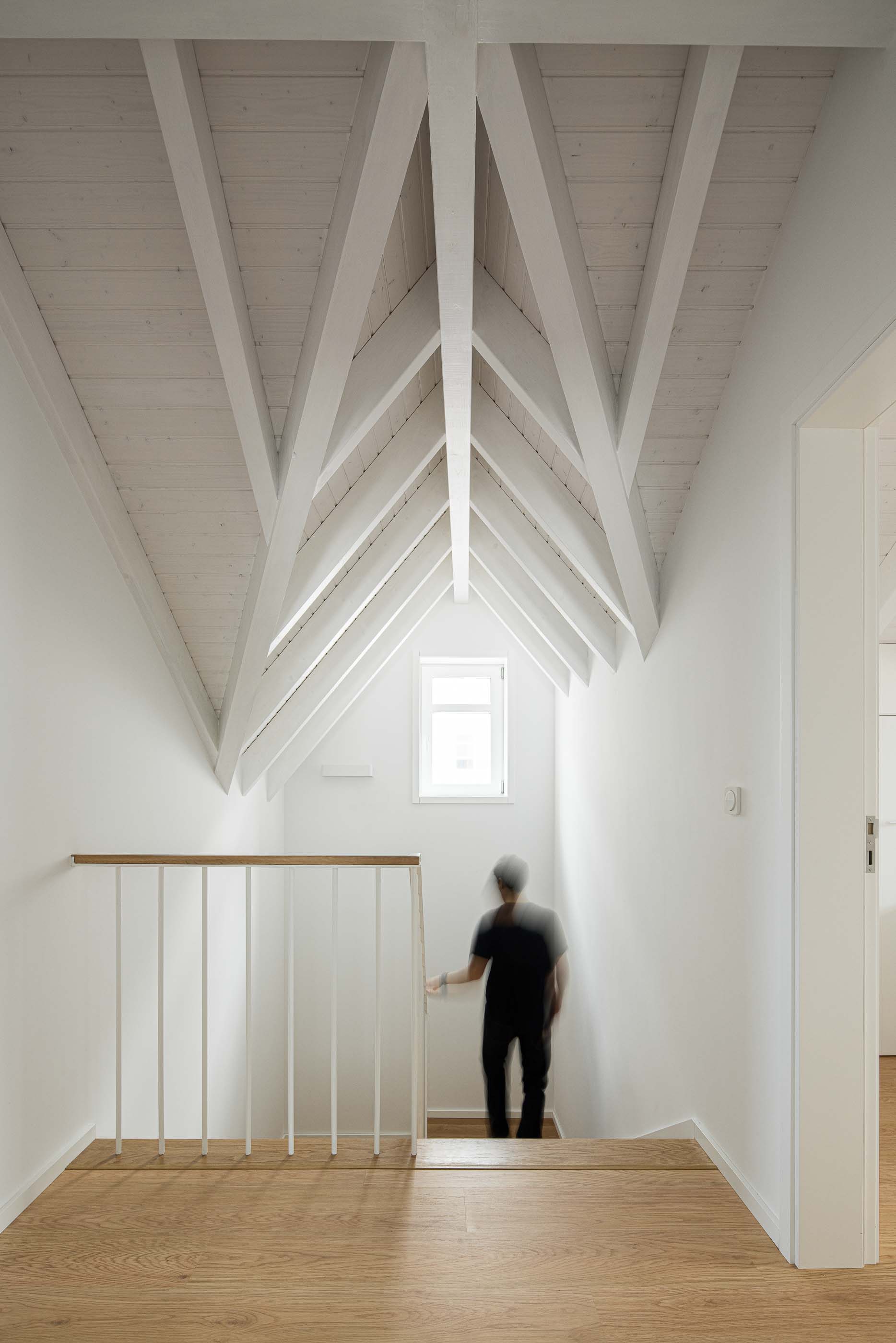 Escadas: Escadas com pavimento de madeira e paredes brancas. Teto com vigas de madeira pintadas de branco. — Casa Clara arquitetura M2Senos Arquitectos em Ílhavo