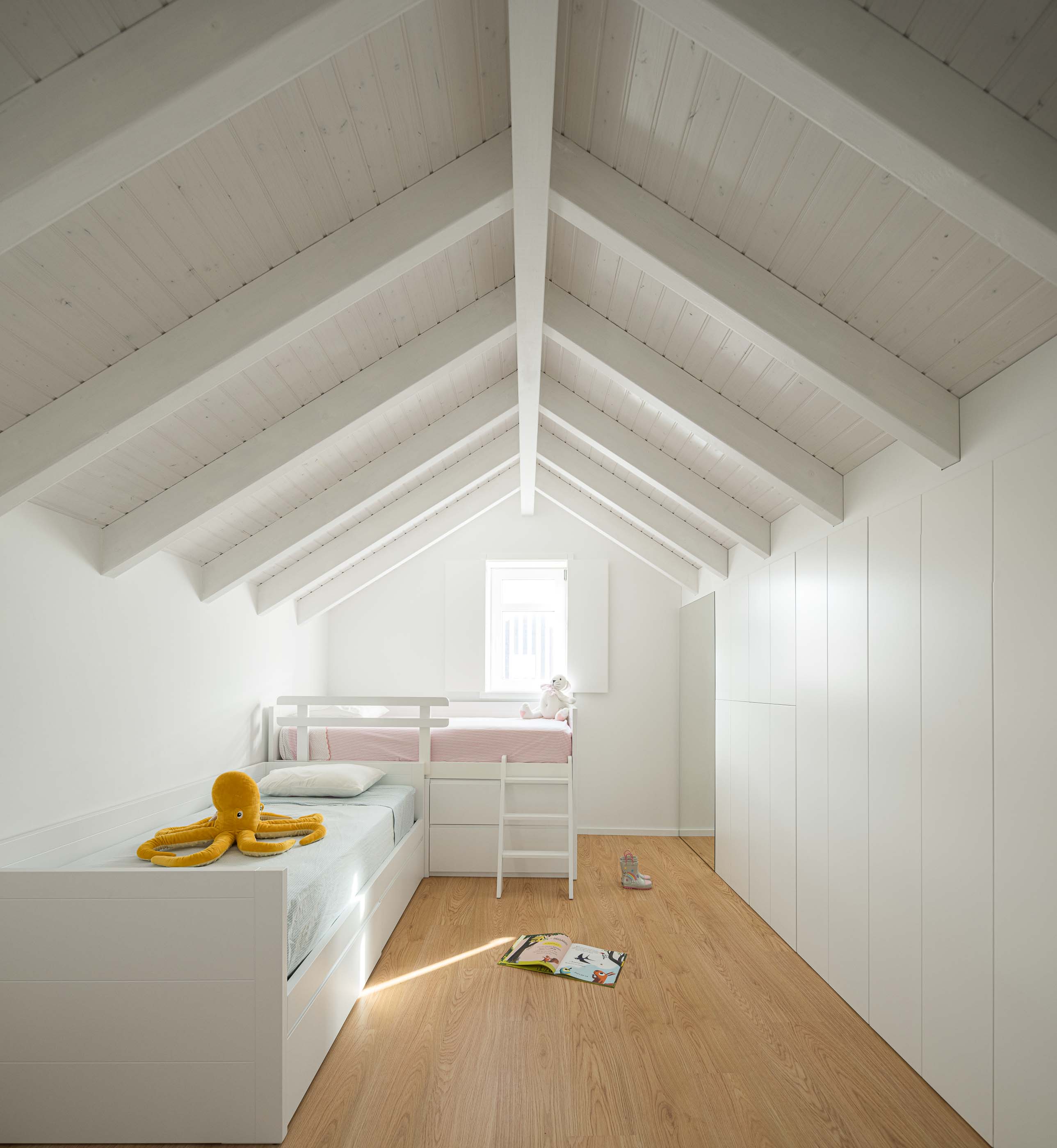 Quarto: Quarto no sótão com camas de beliche brancas, pavimento de madeira e teto com vigas brancas. — Casa Clara arquitetura M2Senos Arquitectos em Ílhavo