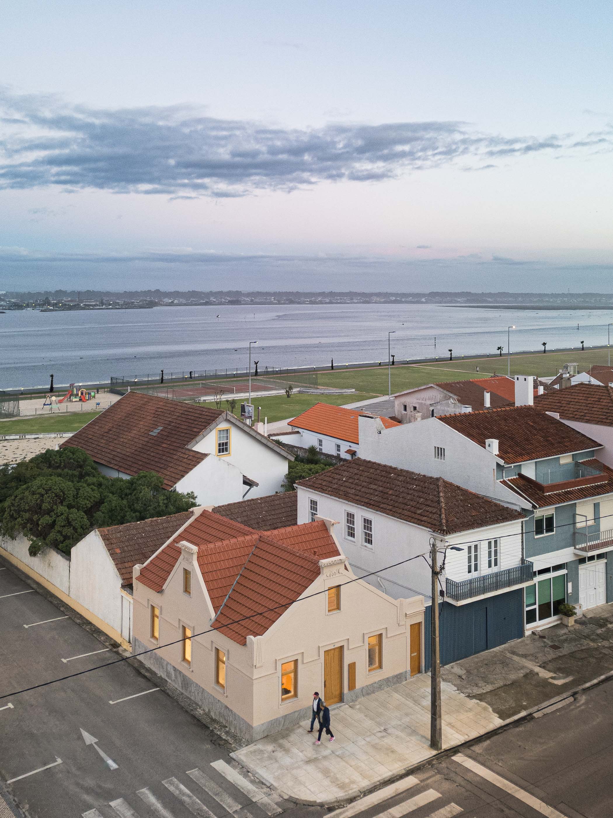 Exterior: Vista aérea da casa com telhado de telha vermelha, fachada bege e envolvente urbana. — Casa Clara arquitetura M2Senos Arquitectos em Ílhavo