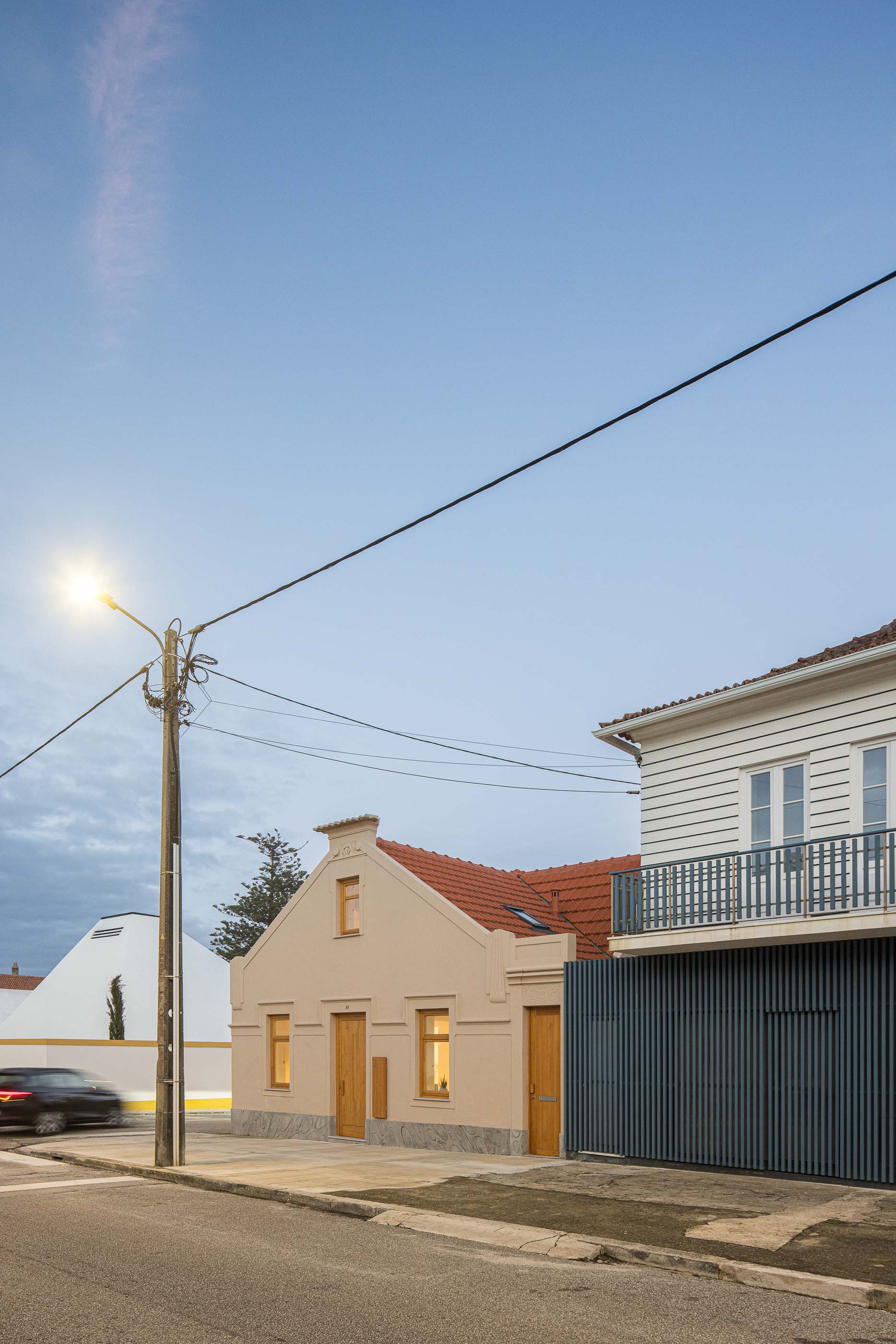 Exterior: Vista da rua da casa com fachada bege e telhado vermelho, integrada na paisagem urbana. — Casa Clara arquitetura M2Senos Arquitectos em Ílhavo