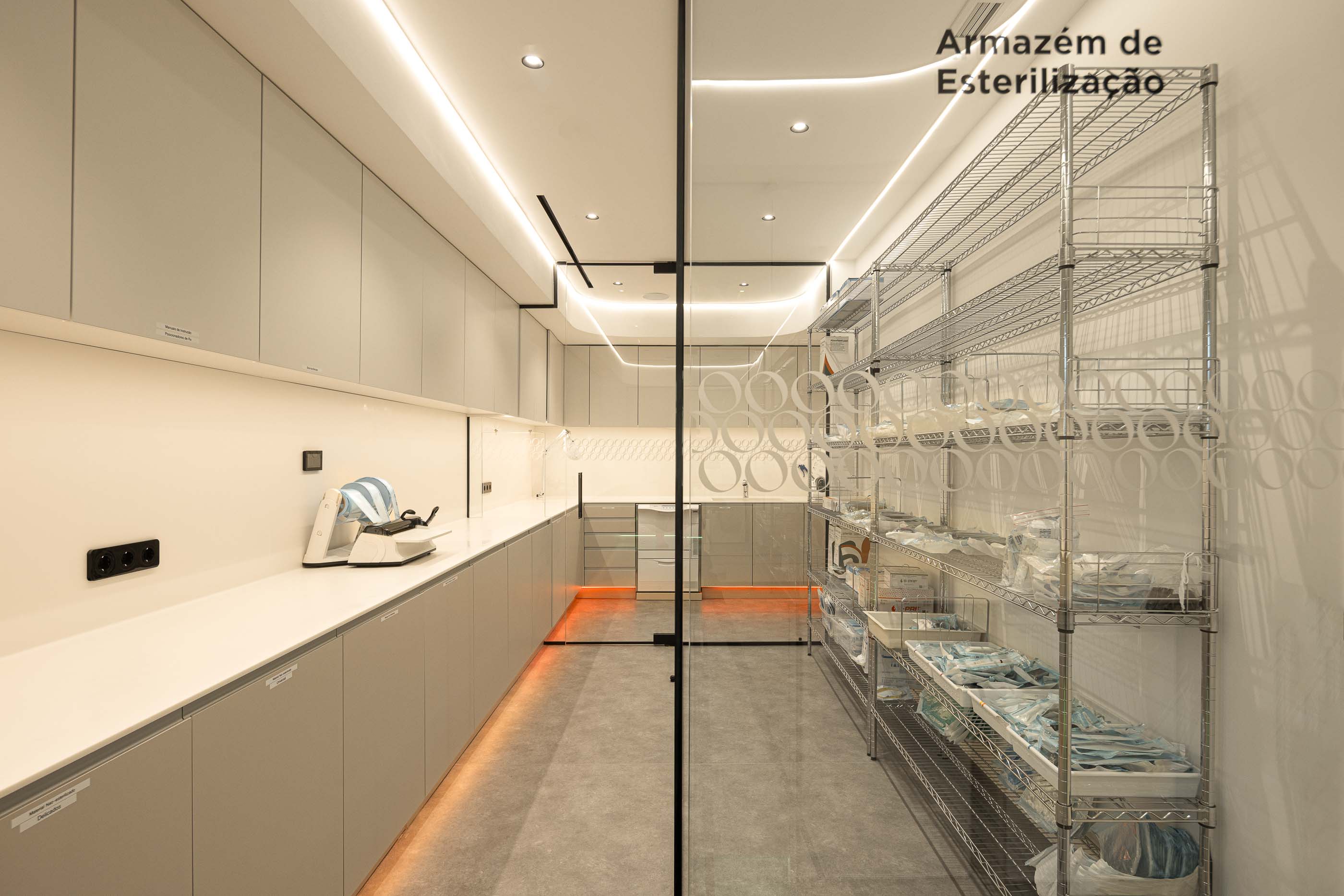 Armazém de Esterilização: Prateleiras metálicas com material esterilizado e bancada com equipamentos de limpeza. — YOU – Clínica Dentária arquitetura Radian Contemporary Architecture em Malveira