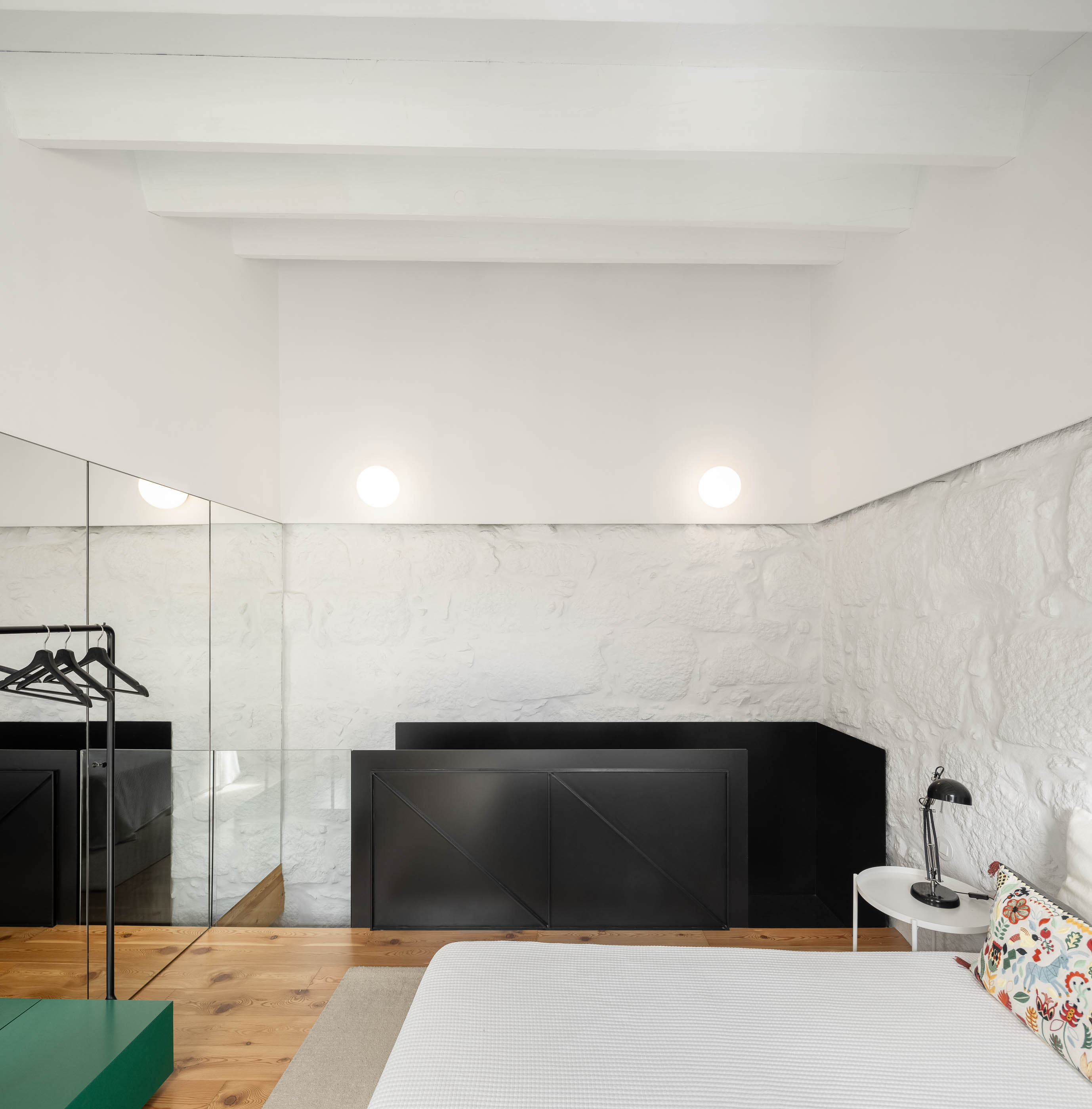 Quarto: Vista geral do quarto com cama, espelho, guarda-roupa preto e pavimento em madeira clara. — Casa Covelo arquitetura spaceworkers em Porto