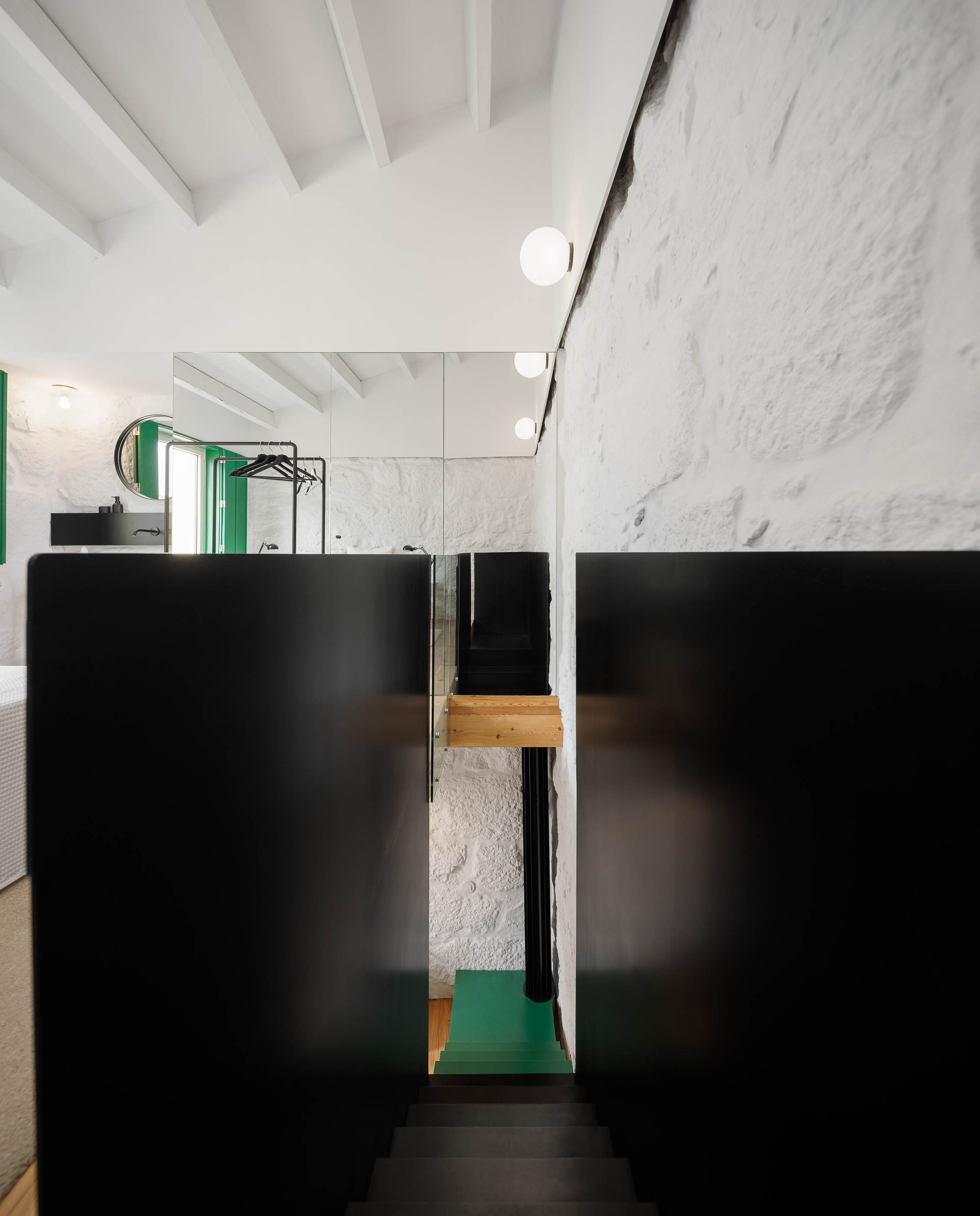 Escada: Vista da escada preta, parede em pedra branca e acesso ao quarto de banho com azulejos verdes. — Casa Covelo arquitetura spaceworkers em Porto