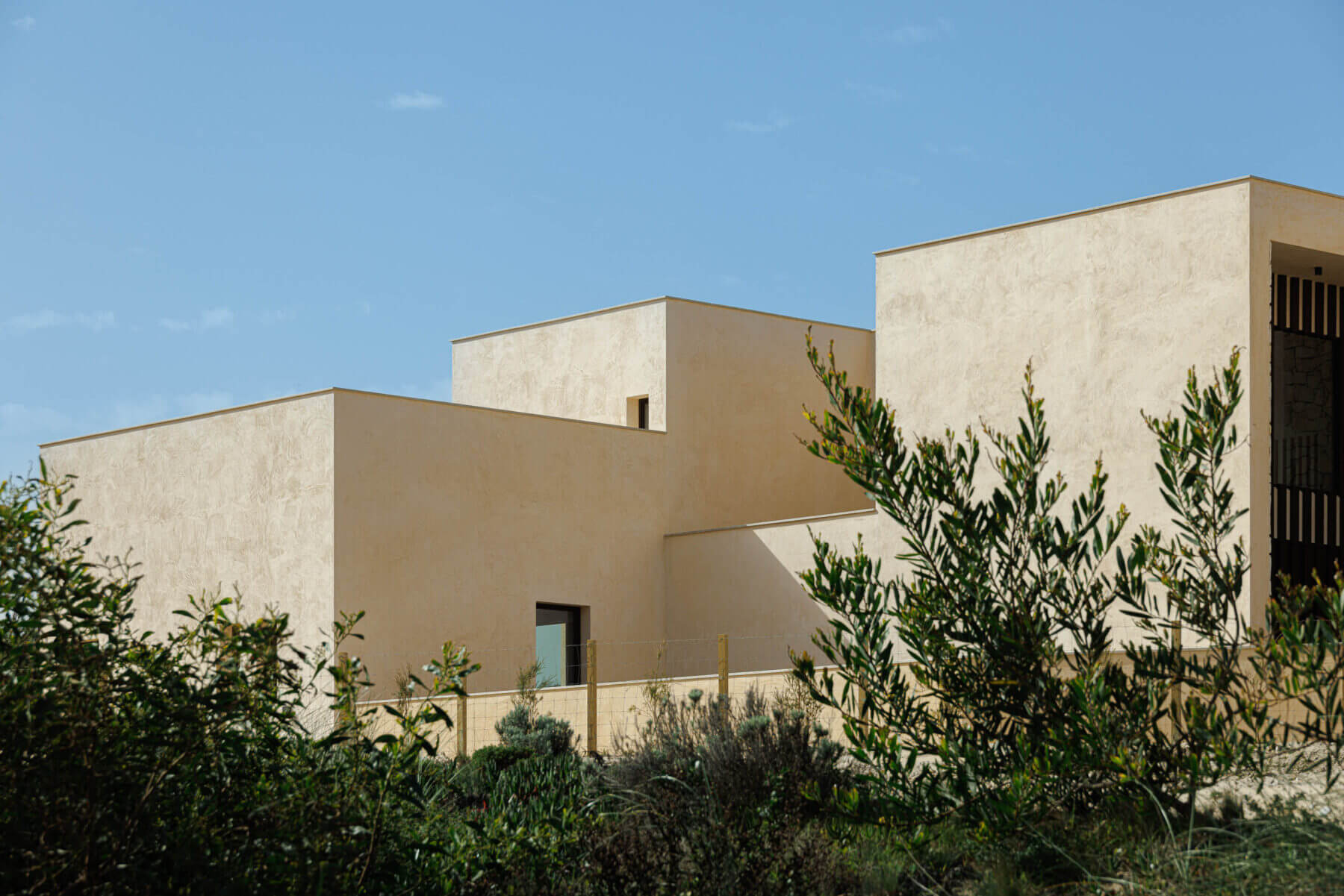 Exterior: Vista da fachada com vegetação rasteira, evidenciando a volumetria da construção. — Parada das Estrelas arquitetura Solano Soto Architecture Studio em Óbidos
