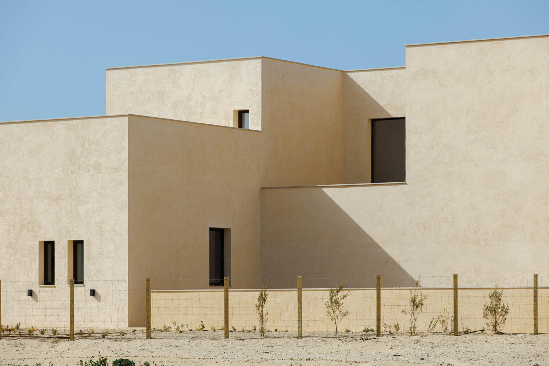 Exterior: Fachada com janelas verticais e horizontais, vedação de madeira e vegetação rasteira. — Parada das Estrelas arquitetura Solano Soto Architecture Studio em Óbidos