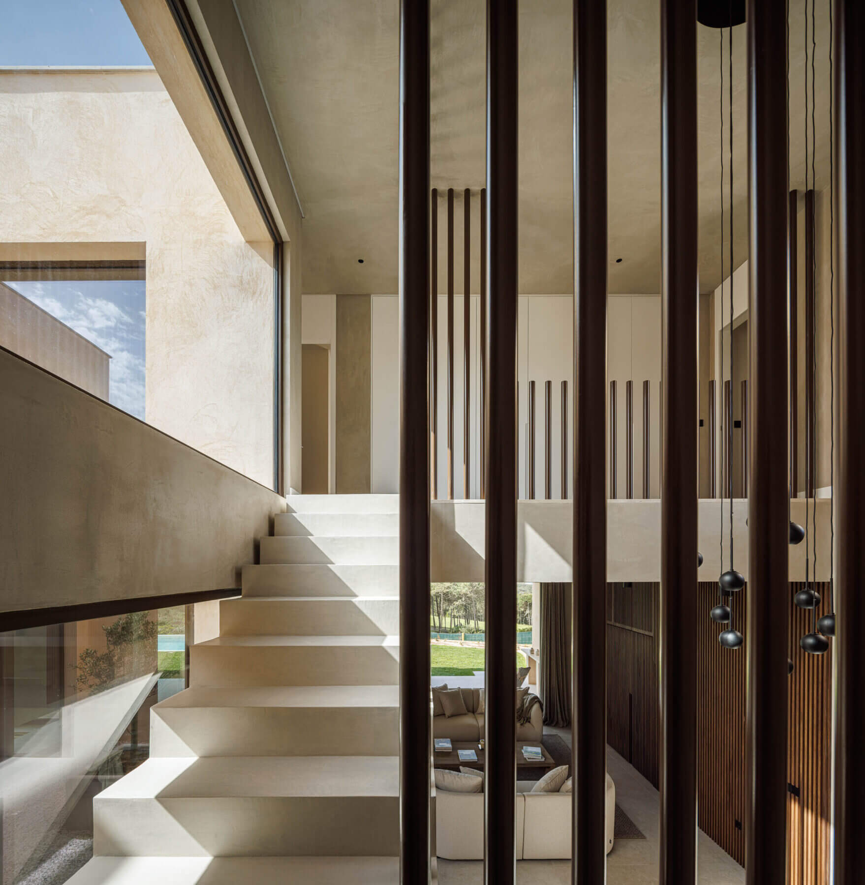 Escada: Vista da escada com ripas de madeira, candeeiros suspensos e acesso ao piso inferior. — Parada das Estrelas arquitetura Solano Soto Architecture Studio em Óbidos