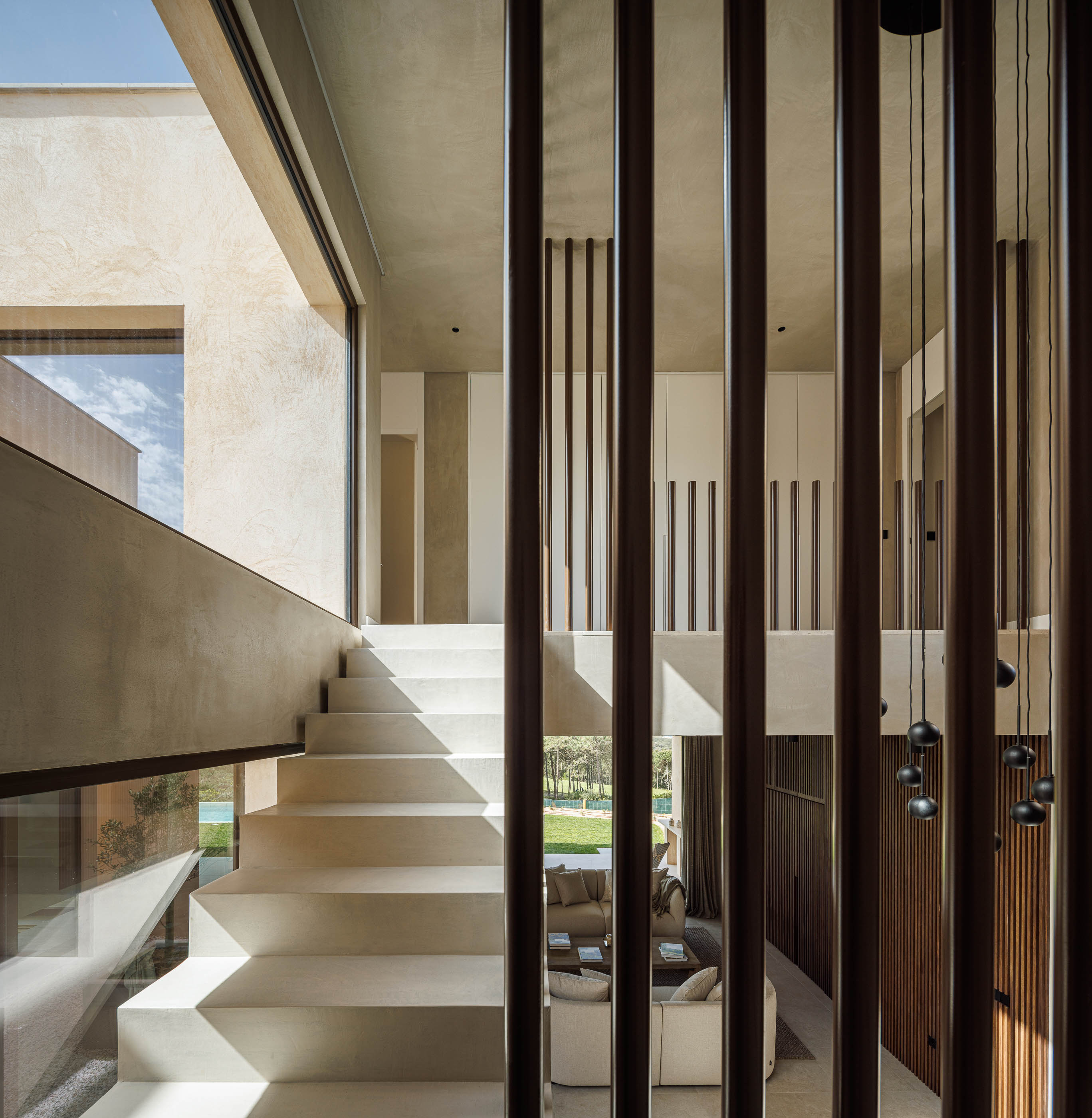 Escada: Vista da escada com ripas de madeira, candeeiros suspensos e acesso ao piso inferior. — Parada das Estrelas arquitetura Solano Soto Architecture Studio em Óbidos