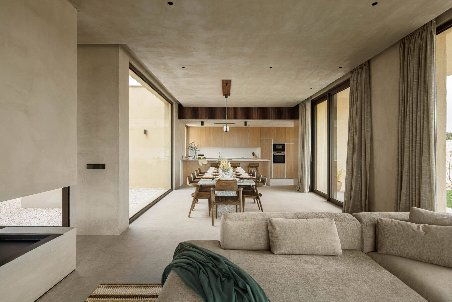 Sala de estar/jantar: Sofá modular, lareira, mesa de jantar e cozinha em plano aberto. — Parada das Estrelas arquitetura Solano Soto Architecture Studio em Óbidos