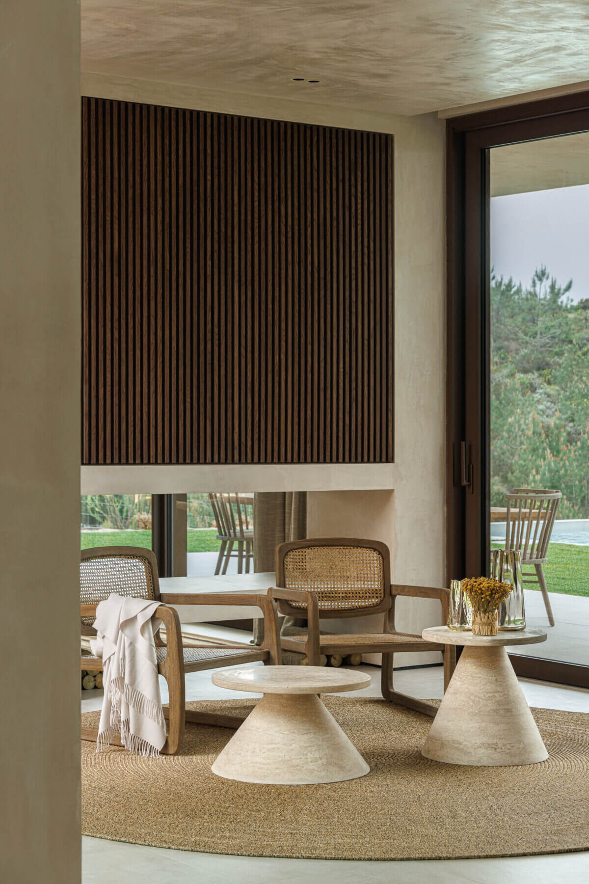 Sala de estar: Cadeiras em madeira e palhinha, mesas de apoio redondas e alcatifa de juta. — Parada das Estrelas arquitetura Solano Soto Architecture Studio em Óbidos