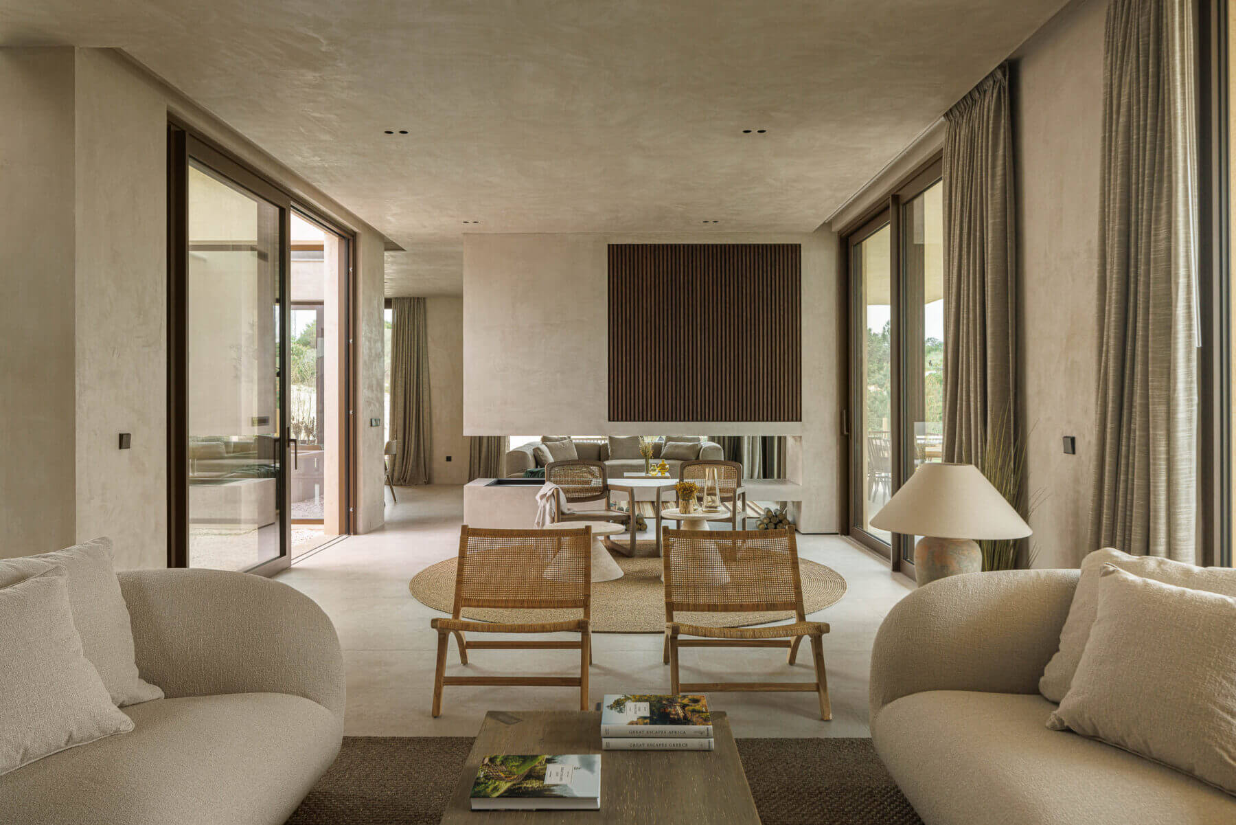 Sala de estar: Sofás em tecido claro, cadeiras em madeira e lareira com ripas verticais. — Parada das Estrelas arquitetura Solano Soto Architecture Studio em Óbidos