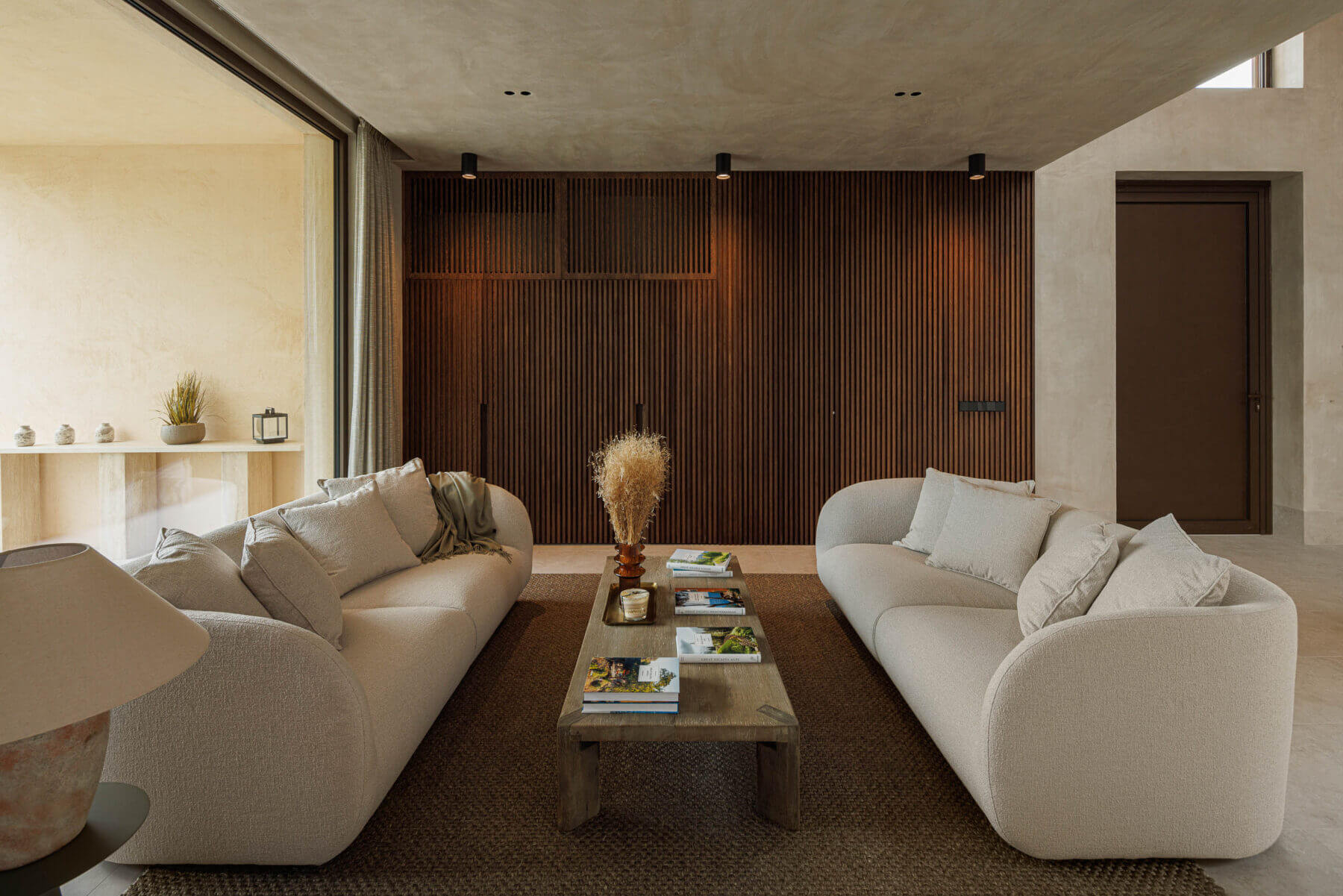 Sala de estar: Sofás em tecido claro, mesa de centro em madeira e ripas verticais na parede. — Parada das Estrelas arquitetura Solano Soto Architecture Studio em Óbidos