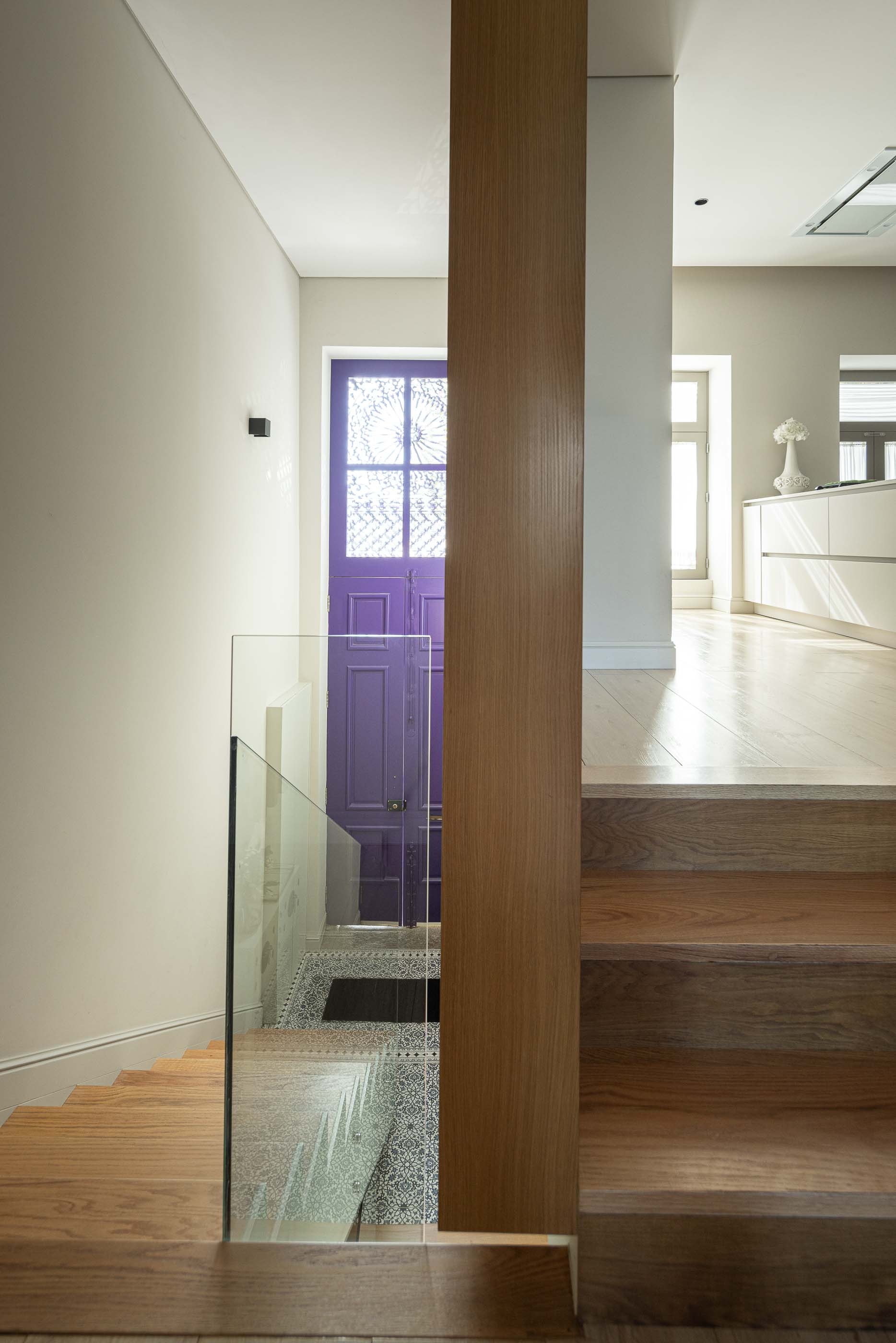 Escadas: Escadas em madeira com guarda em vidro, coluna em madeira e vista para a porta de entrada roxa. — Casa do Parque IV arquitetura Ricardo Azevedo Arquitecto em Santo Tirso