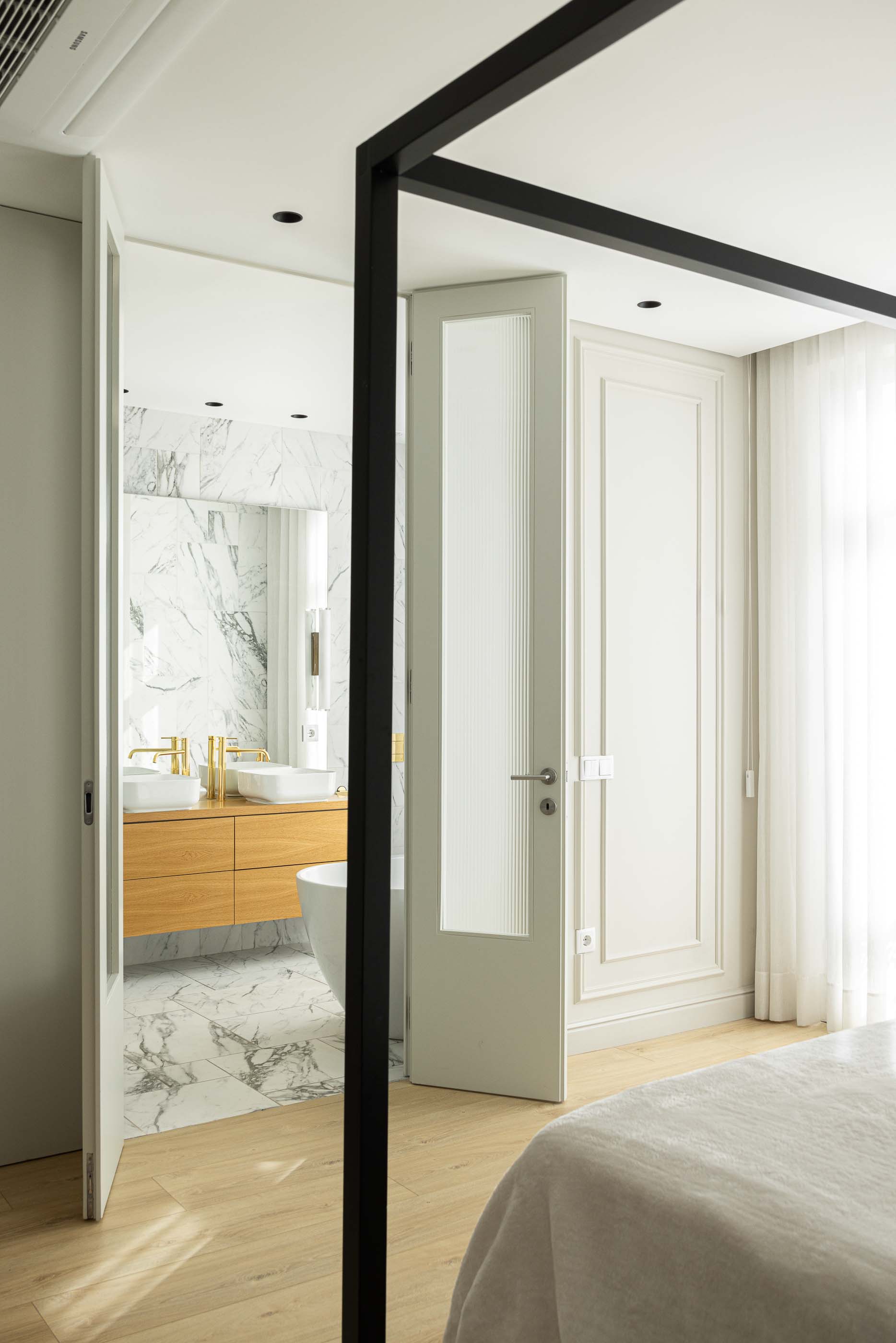 Quarto: Vista do quarto com cama de dossel preta para a casa de banho com revestimento em mármore. — Casa do Parque IV arquitetura Ricardo Azevedo Arquitecto em Santo Tirso