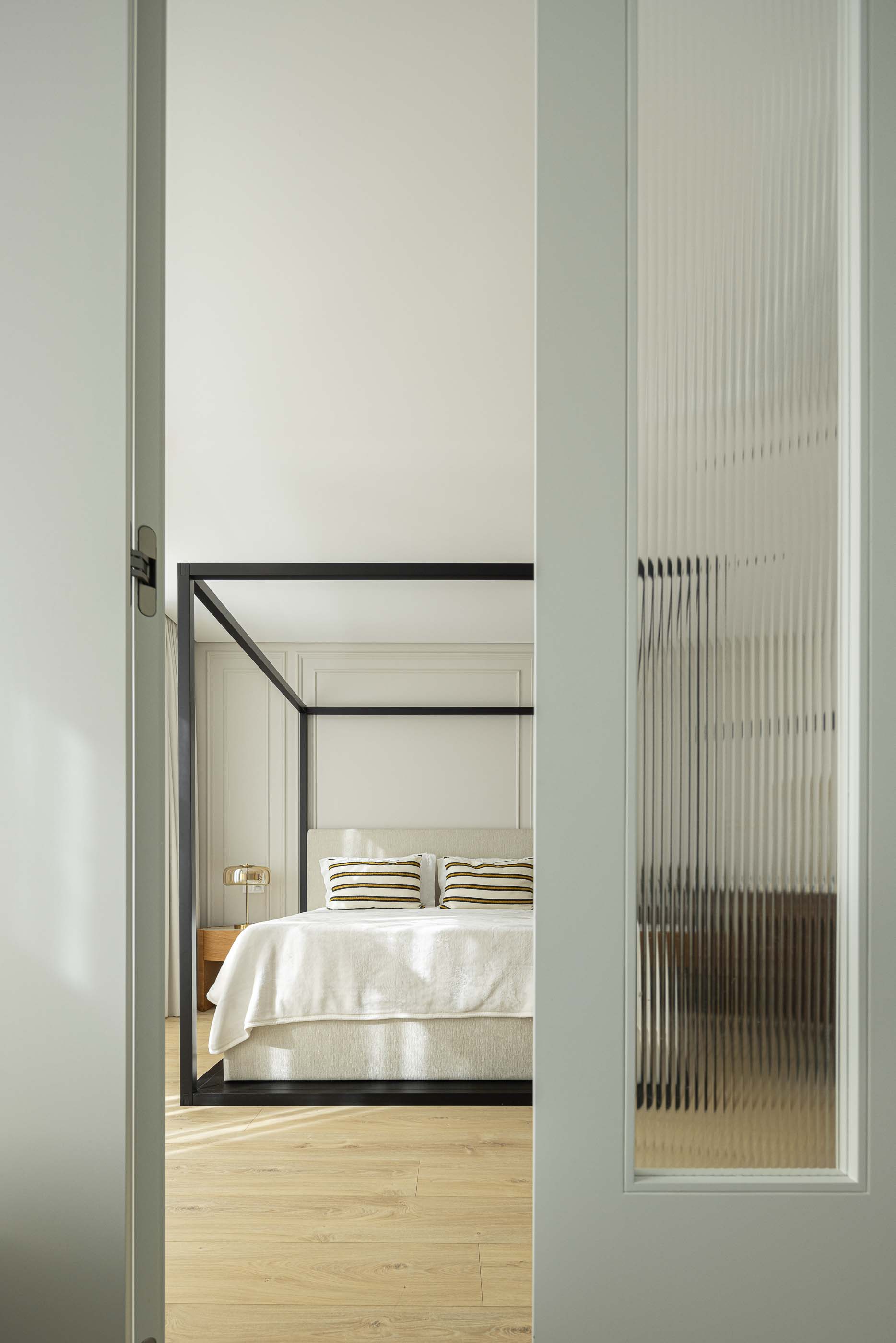 Quarto: Vista do quarto com cama de dossel preta através de porta de vidro canelado. — Casa do Parque IV arquitetura Ricardo Azevedo Arquitecto em Santo Tirso