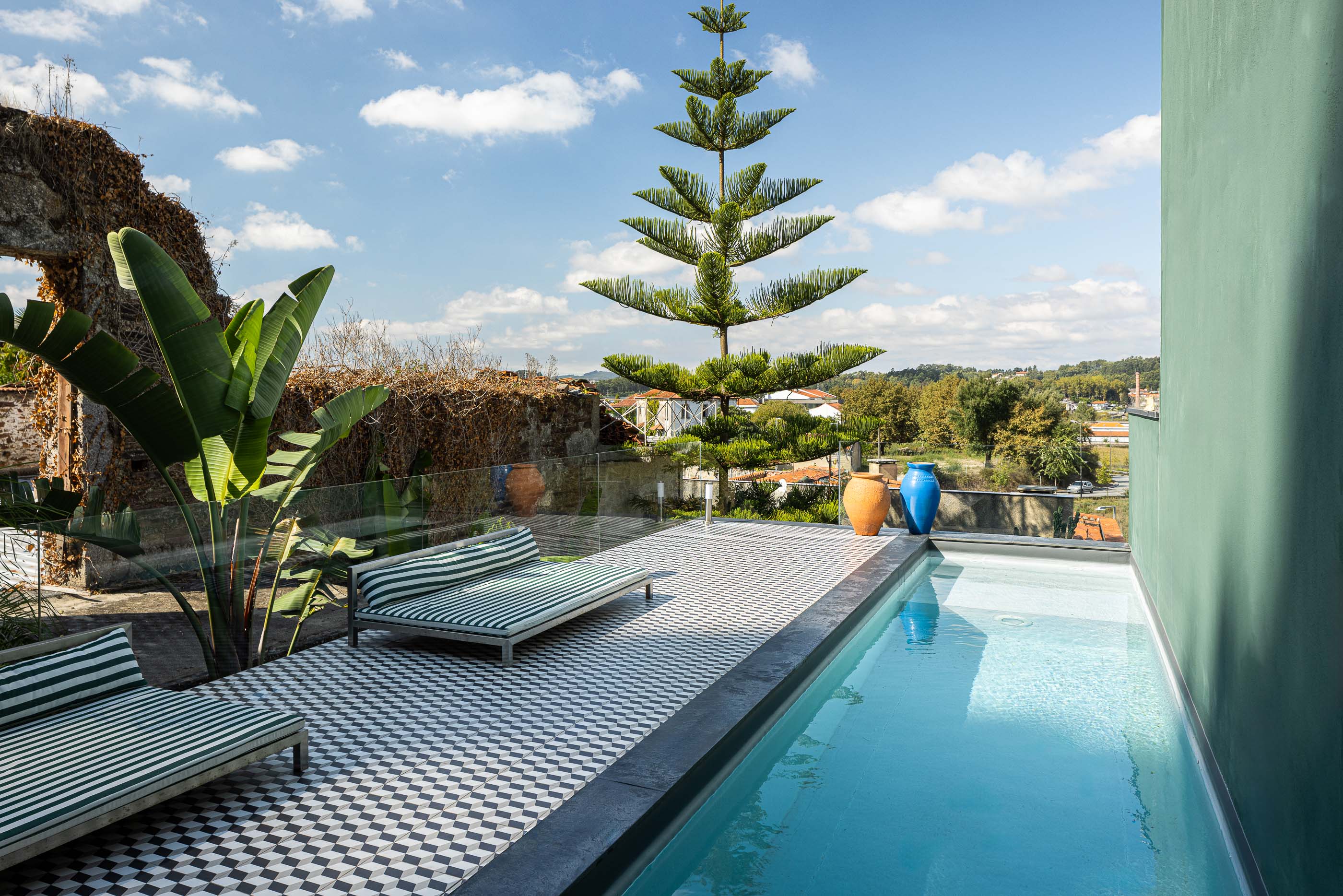 Exterior: Piscina com espreguiçadeiras, pavimento geométrico e ruínas em pedra ao fundo. — Casa do Parque IV arquitetura Ricardo Azevedo Arquitecto em Santo Tirso