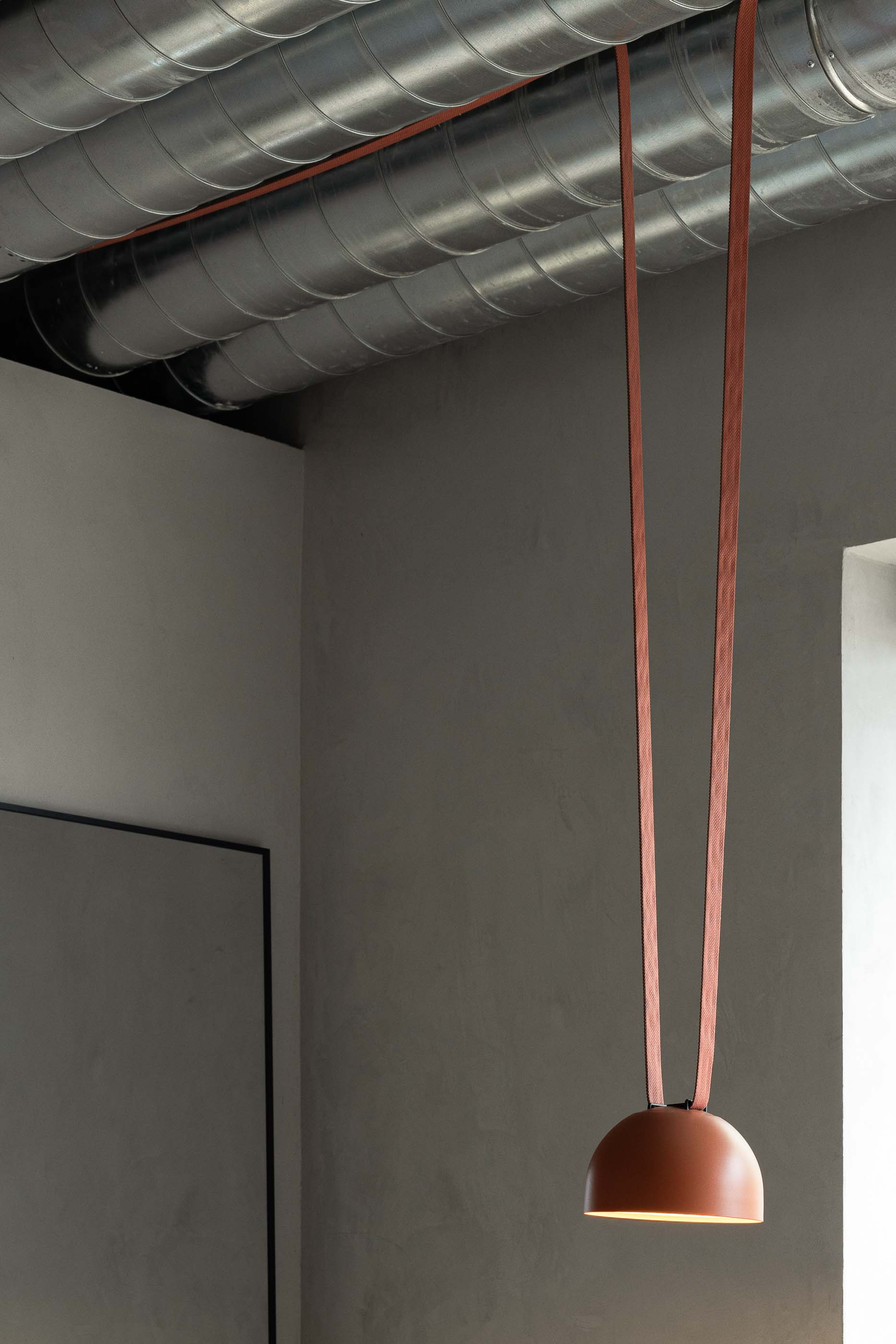 Tecto: Detalhe de tubagens expostas no tecto com candeeiro suspenso por fitas cor de tijolo. — KI.art.music.coffee arquitetura MAT Arquitetura e Interiores em Porto
