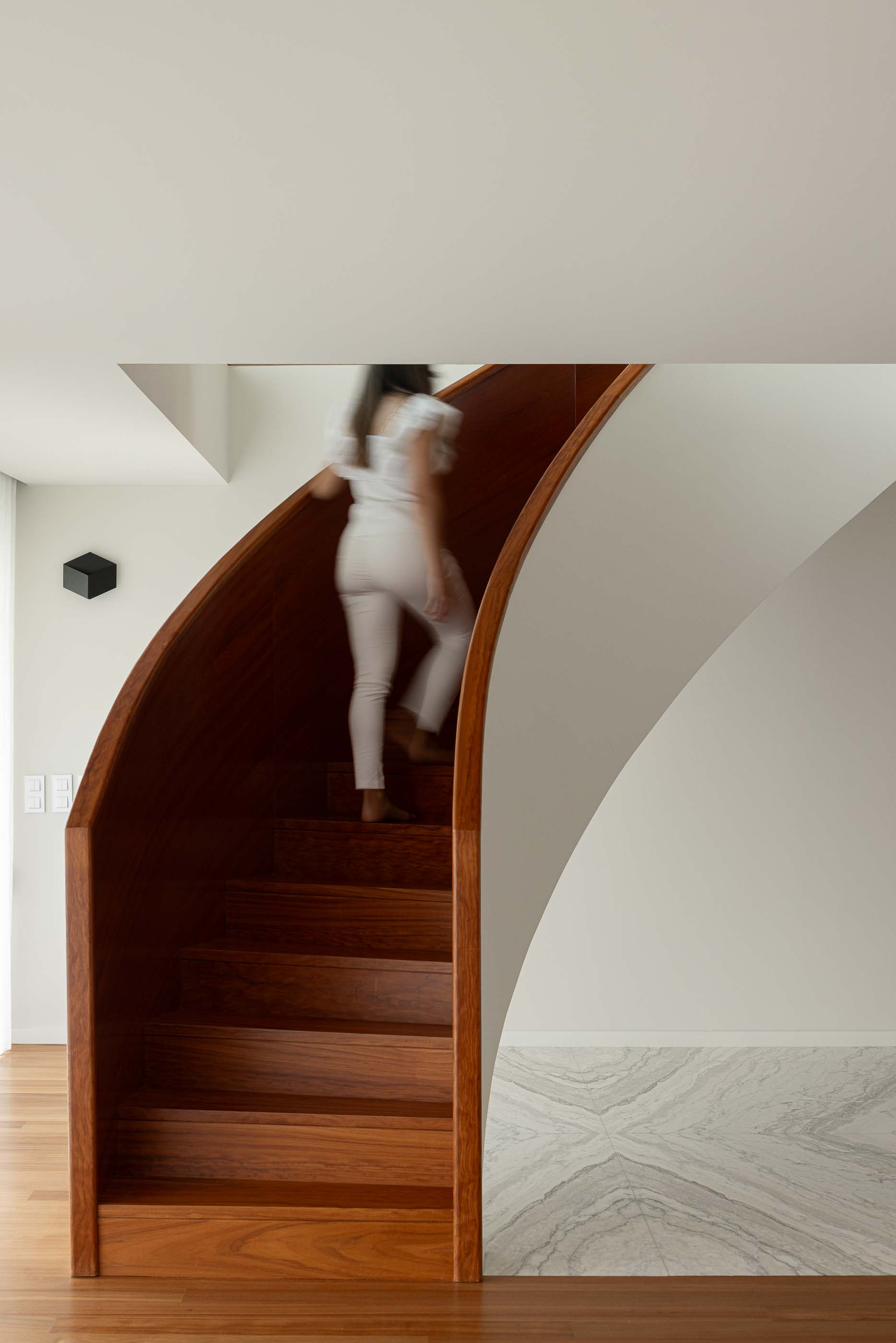 Escadas: Escadas em madeira com corrimão curvo e parede branca. Iluminação indireta e design elegante. — Casa da Encosta arquitetura Ricardo Azevedo Arquitecto em Santo Tirso