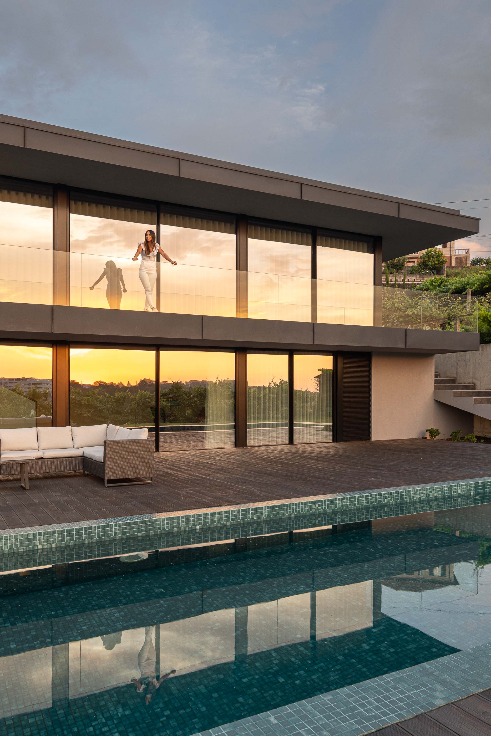 Exterior: Vista da piscina e da fachada da casa com varanda e zona de estar exterior. Arquitetura moderna e minimalista. — Casa da Encosta arquitetura Ricardo Azevedo Arquitecto em Santo Tirso