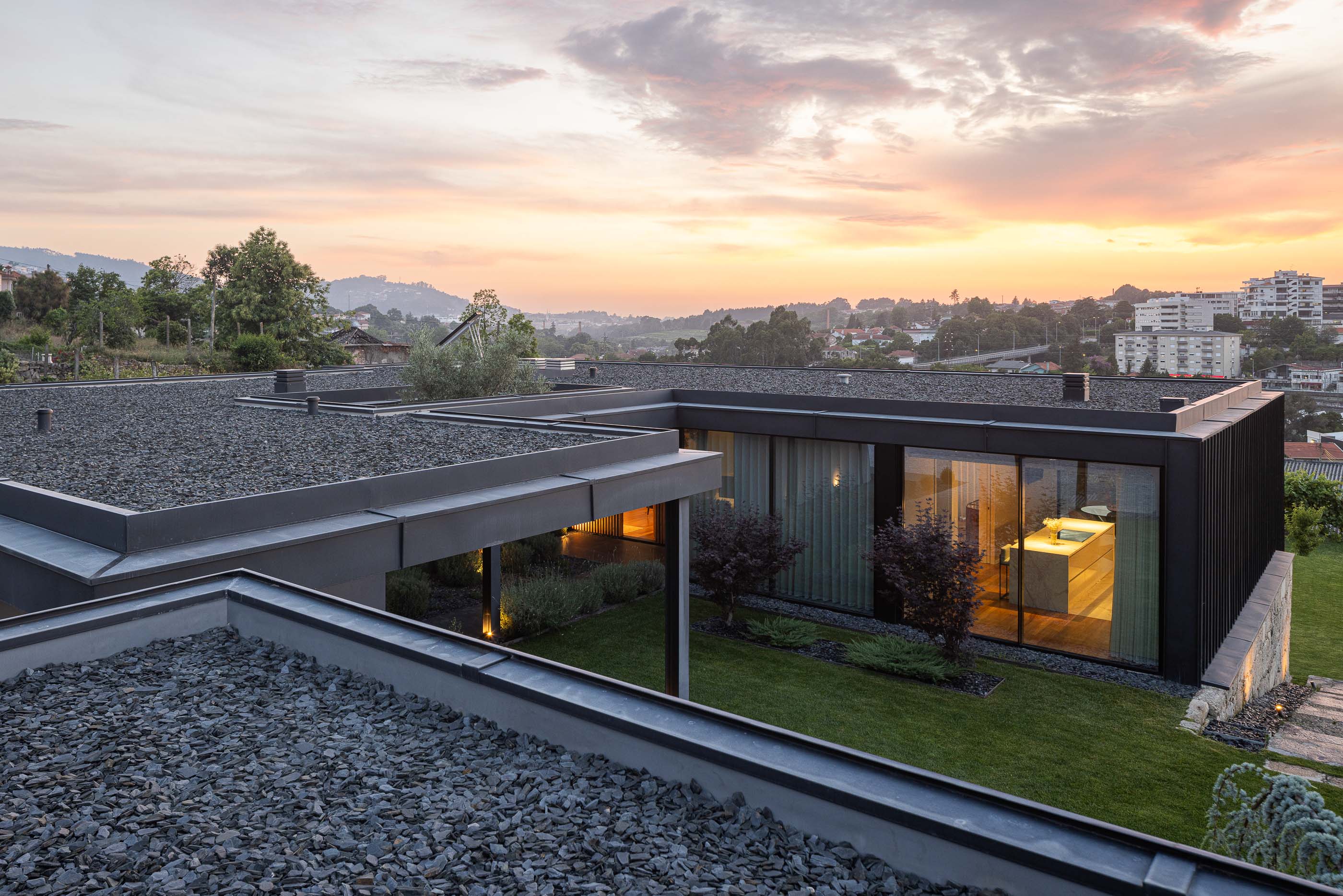 Exterior: Vista geral da casa com pátio interior, jardim e vinha ao pôr do sol. Arquitetura moderna e minimalista. — Casa da Encosta arquitetura Ricardo Azevedo Arquitecto em Santo Tirso