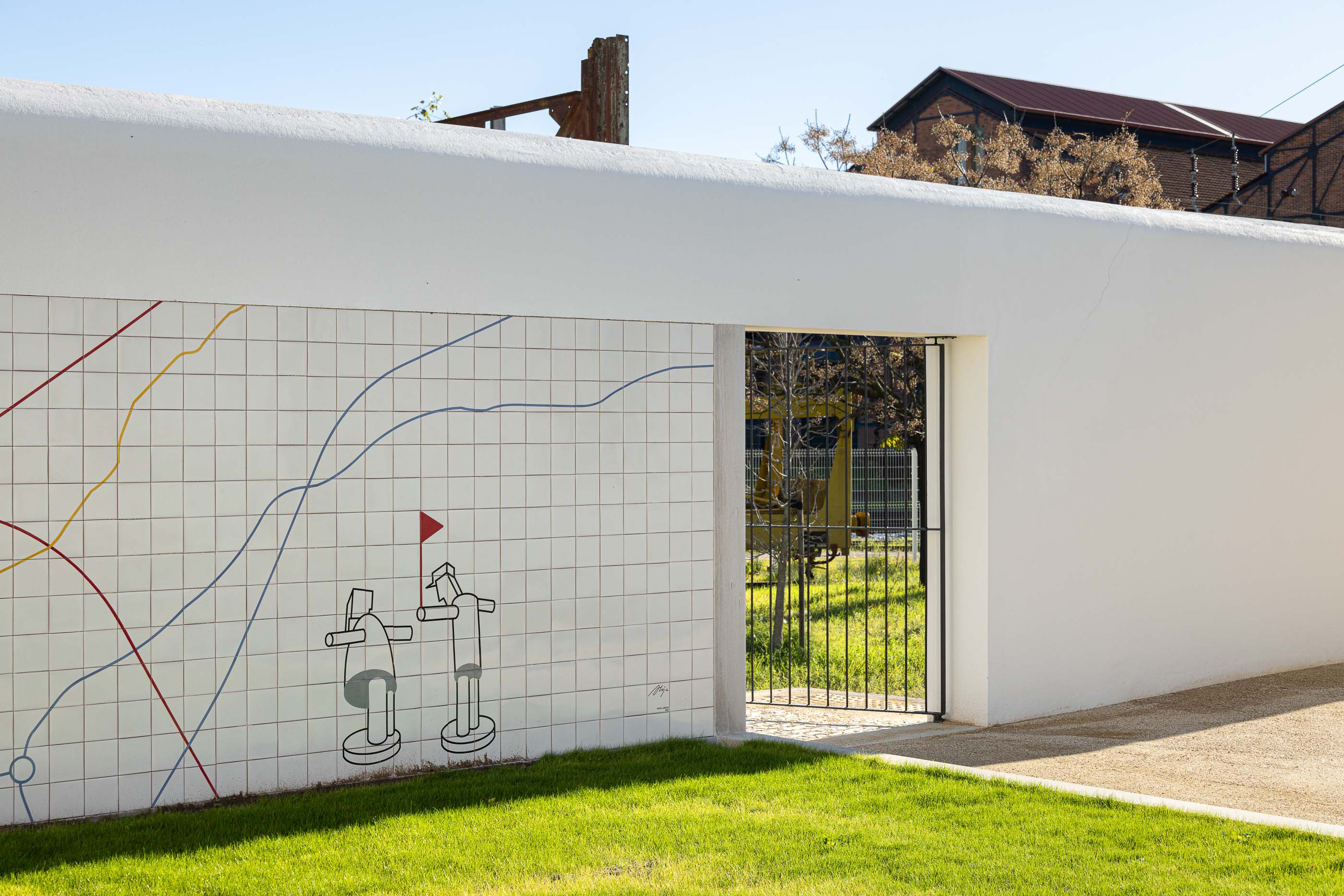 Exterior: Muro revestido com azulejos brancos e desenho linear a cores, com portão de acesso ao pátio. — Reabilitação Urbana do Bairro do Boneco arquitetura Adarq - André David Arquitecto em Entroncamento