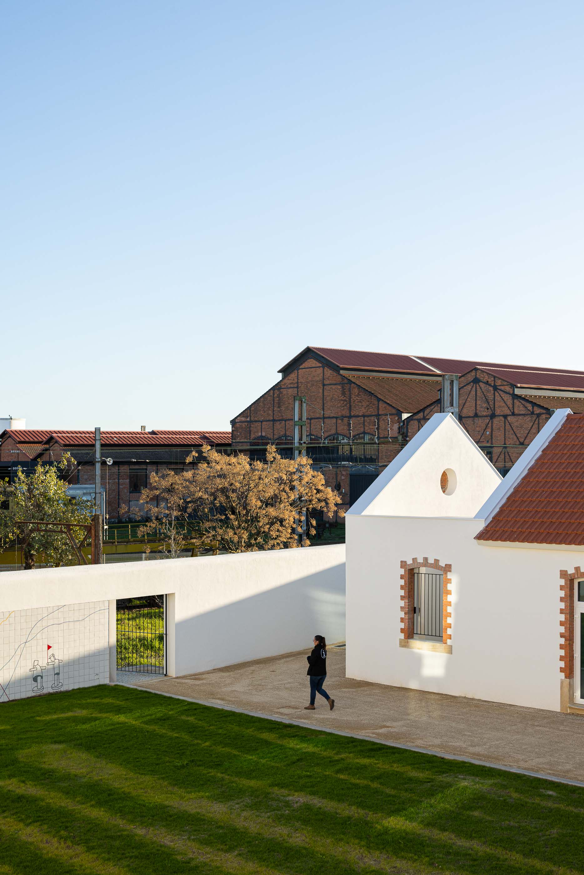 Exterior: Edifícios brancos com telhado cerâmico, muro com revestimento cerâmico e armazéns ferroviários. — Reabilitação Urbana do Bairro do Boneco arquitetura Adarq - André David Arquitecto em Entroncamento