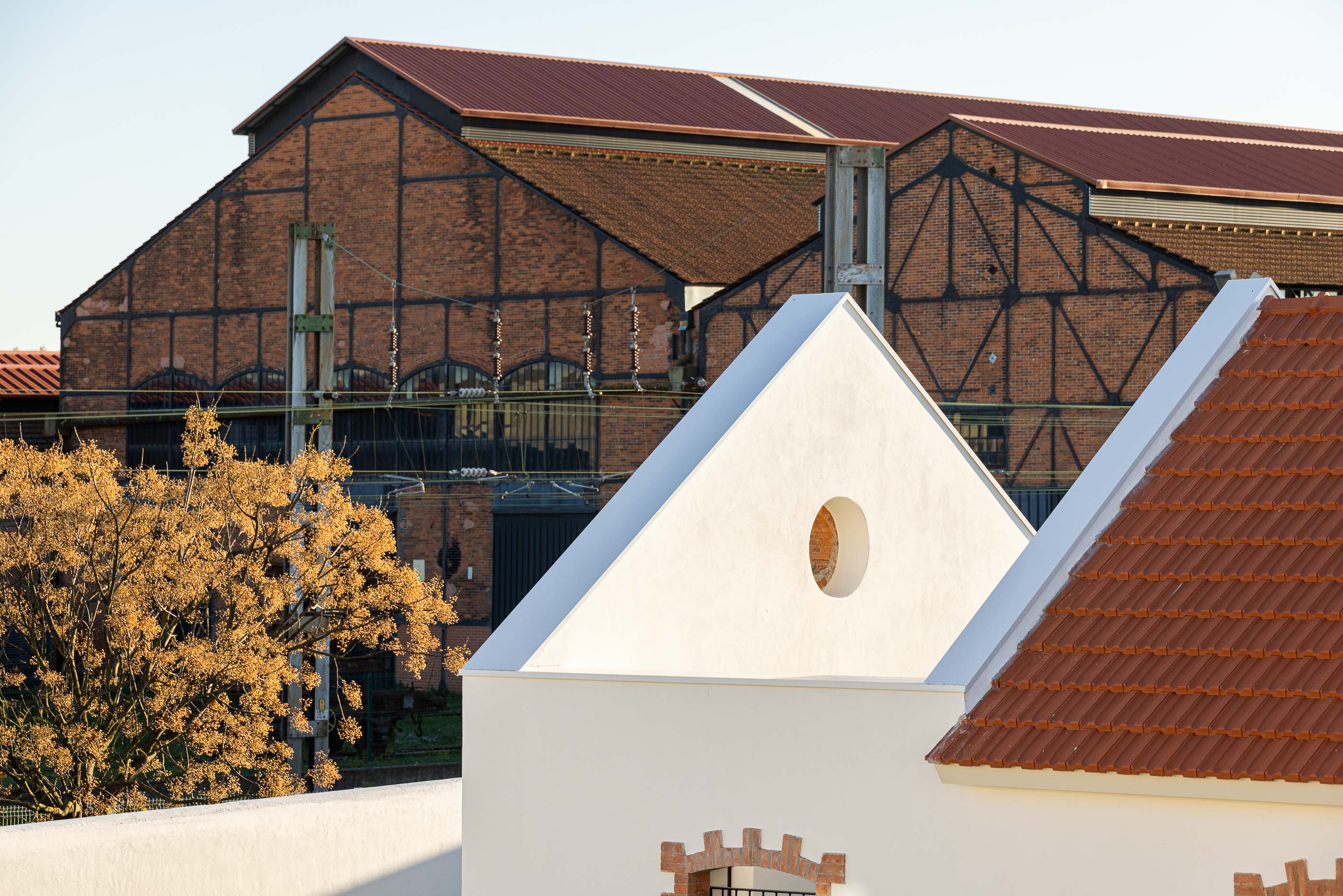 Detalhe exterior: Edifícios brancos com telhado cerâmico e armazéns ferroviários em tijolo. — Reabilitação Urbana do Bairro do Boneco arquitetura Adarq - André David Arquitecto em Entroncamento