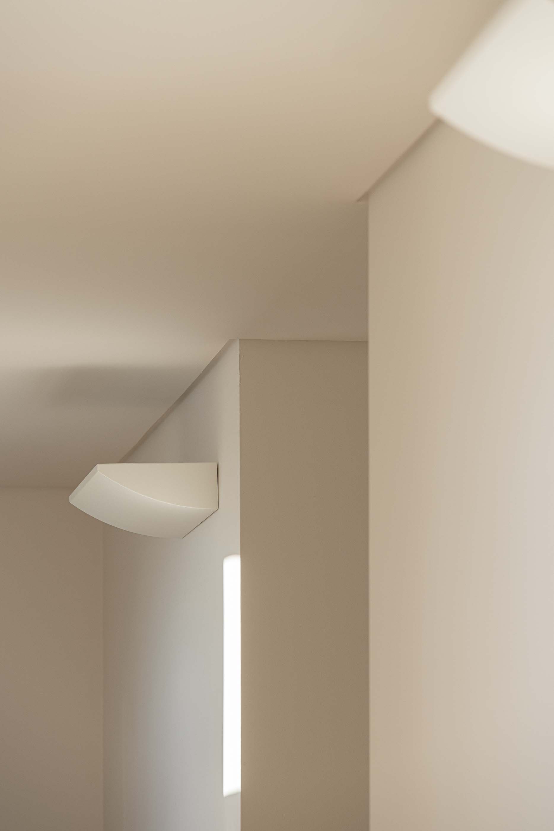 Detalhe interior: Candeeiro de parede branco, com iluminação indireta. — Reabilitação Urbana do Bairro do Boneco arquitetura Adarq - André David Arquitecto em Entroncamento
