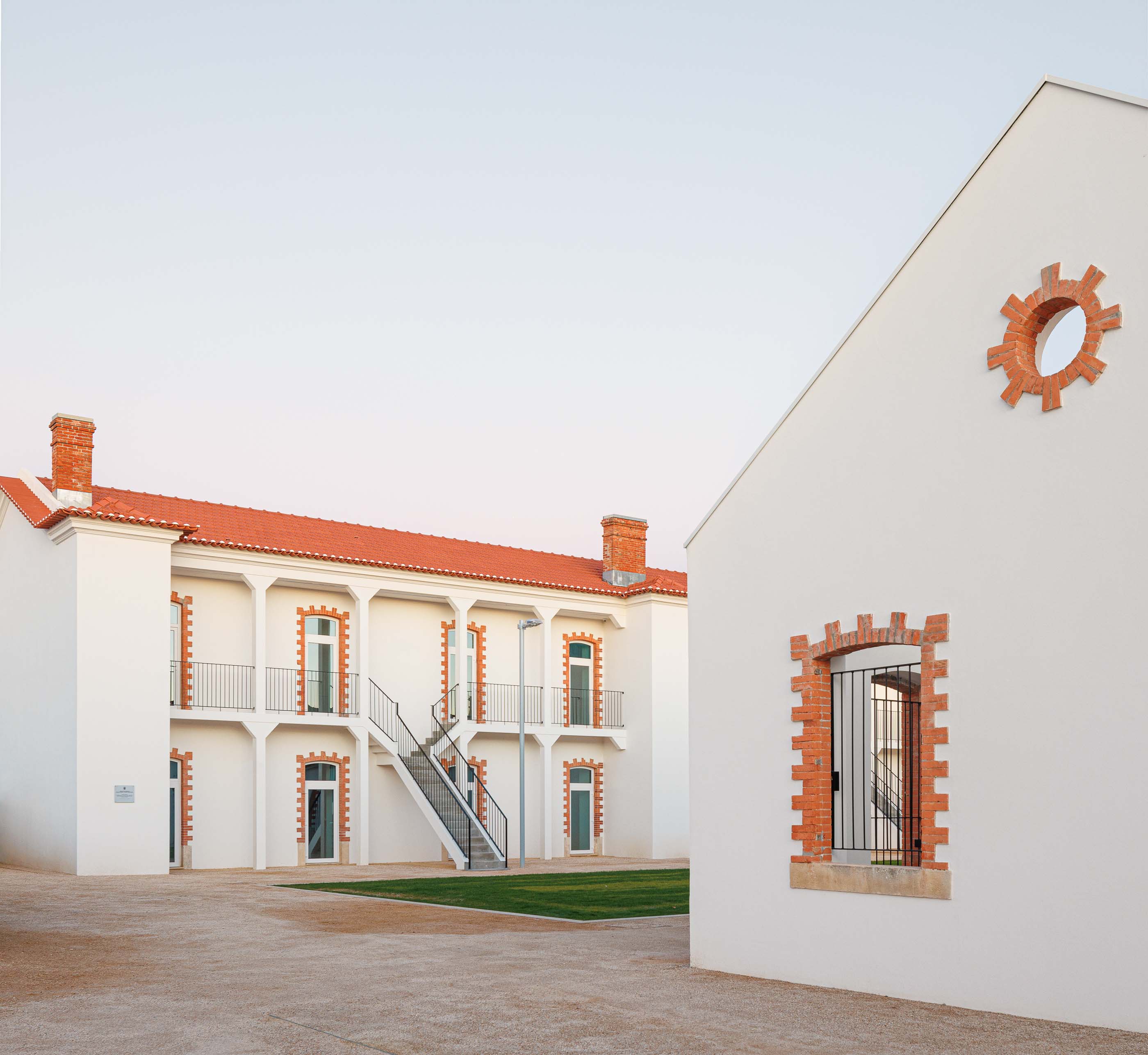 Exterior: Edifícios brancos com telhado cerâmico e óculo circular em tijolo aparente. — Reabilitação Urbana do Bairro do Boneco arquitetura Adarq - André David Arquitecto em Entroncamento