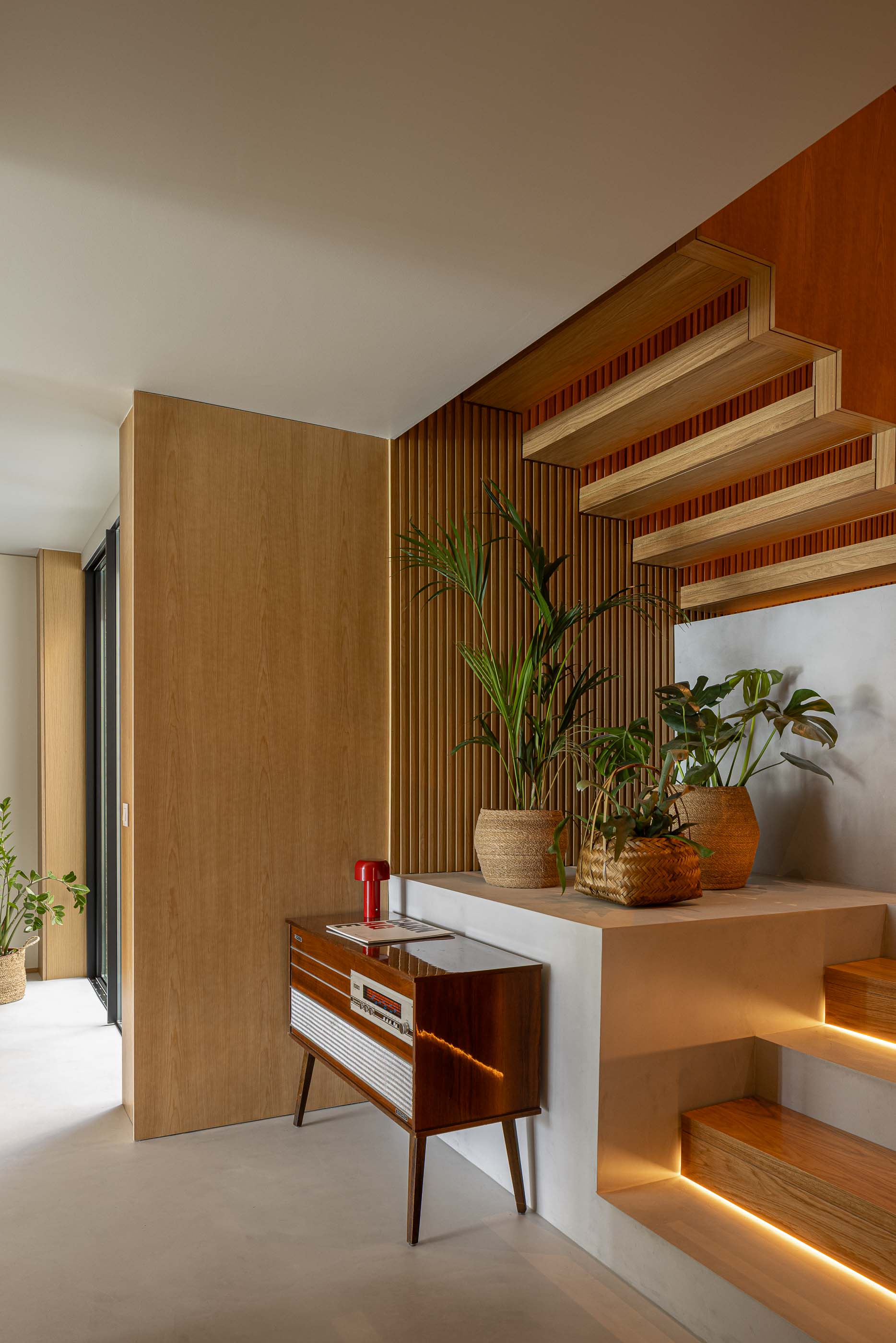 Hall de entrada: Escadas em madeira com iluminação indireta, móvel vintage e plantas. — Casa M arquitetura silverline em Vila Nova de Gaia