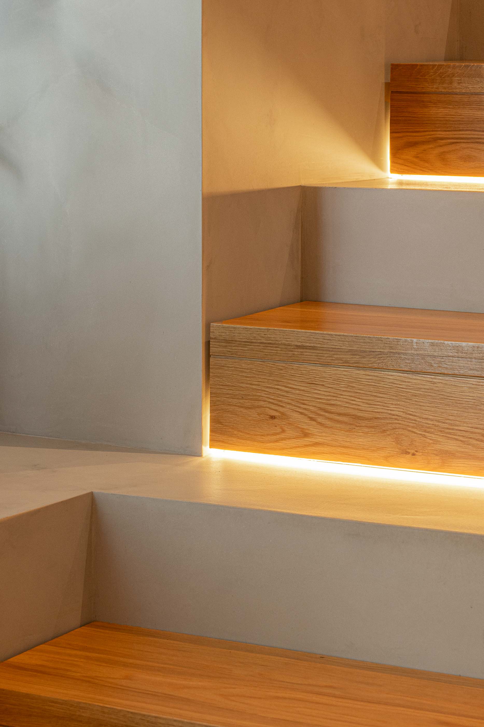 Escadas: Detalhe da iluminação indireta embutida nos degraus de madeira. — Casa M arquitetura silverline em Vila Nova de Gaia
