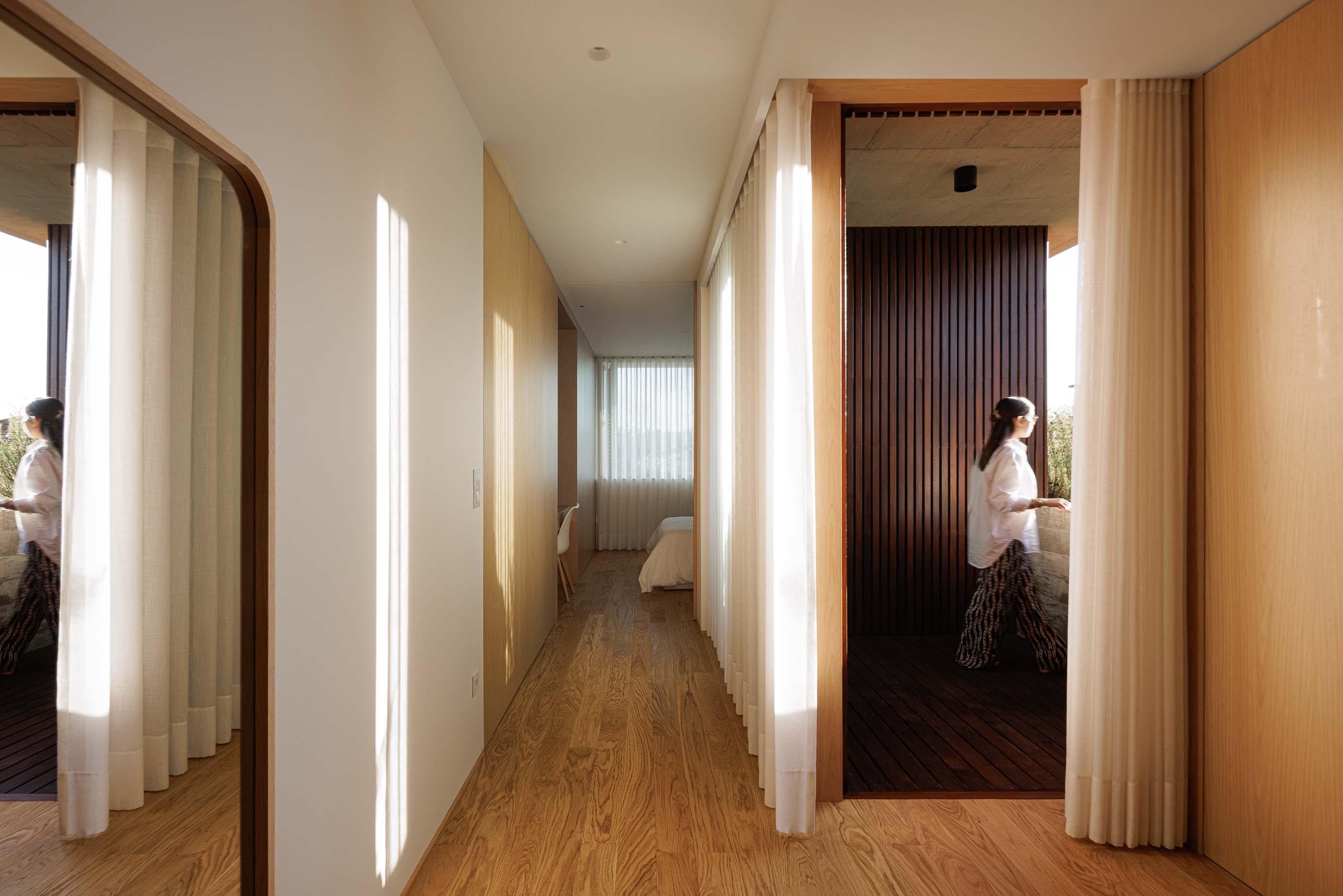 Corredor: Pavimento em madeira, paredes revestidas a madeira e cortinas brancas. — Casa M arquitetura silverline em Vila Nova de Gaia