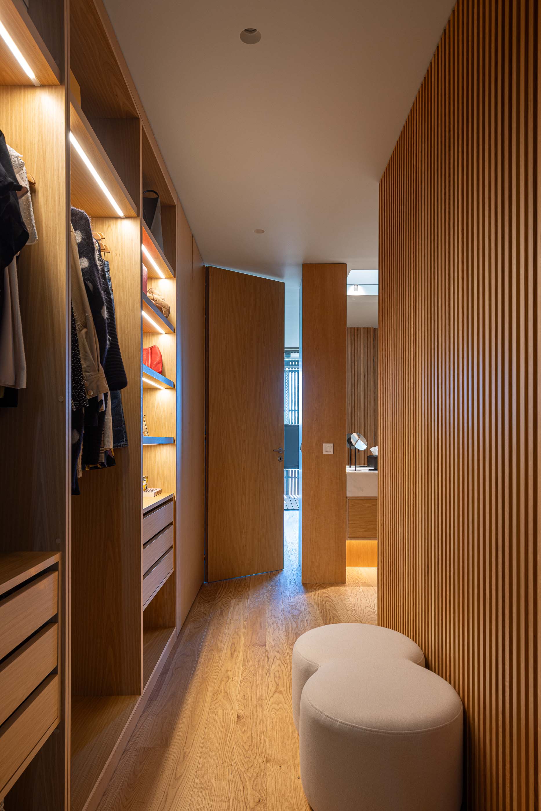 Closet: Armários em madeira com iluminação embutida e pavimento em madeira. — Casa M arquitetura silverline em Vila Nova de Gaia