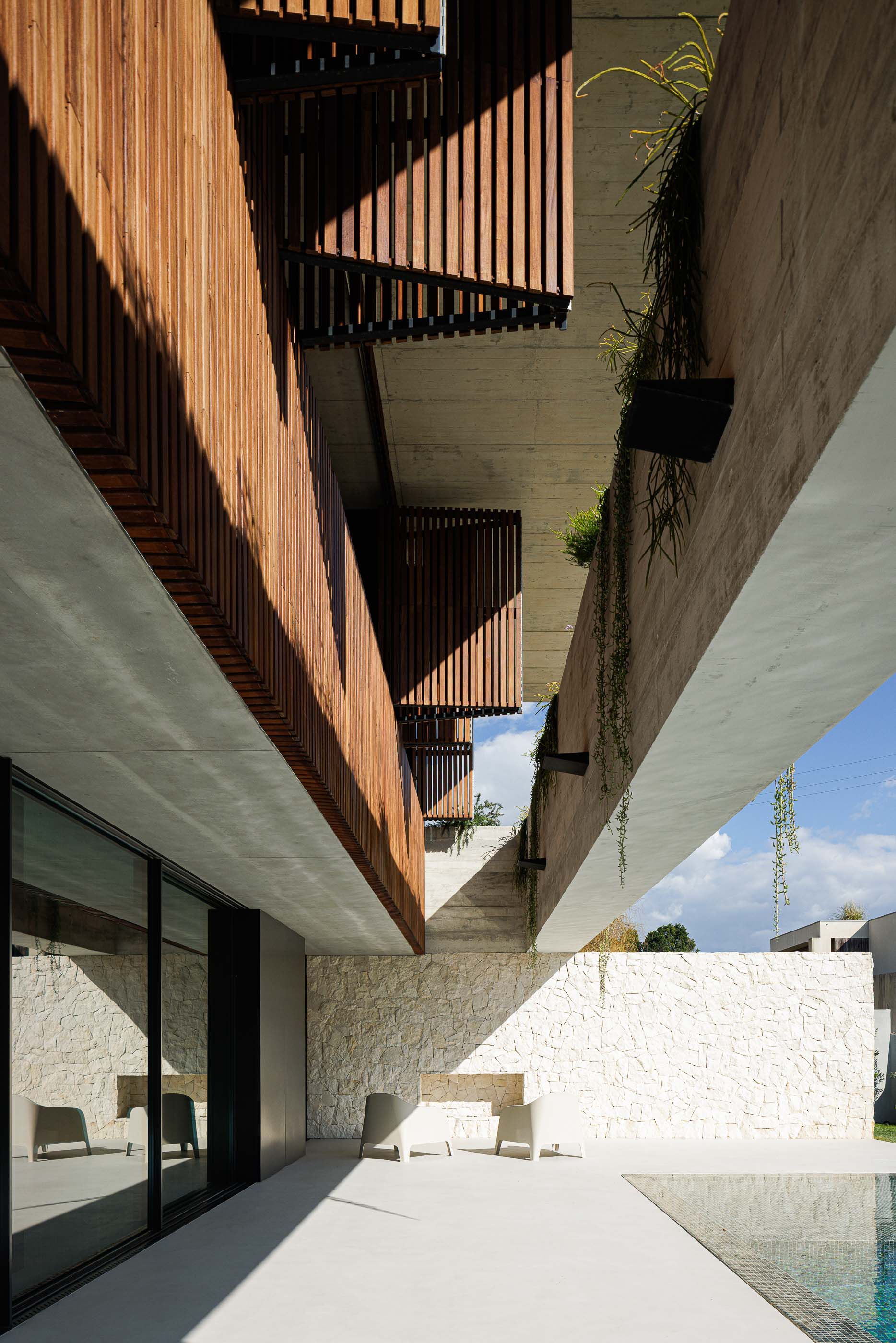 Exterior: Fachada com portadas de madeira, betão aparente e piscina. — Casa M arquitetura silverline em Vila Nova de Gaia