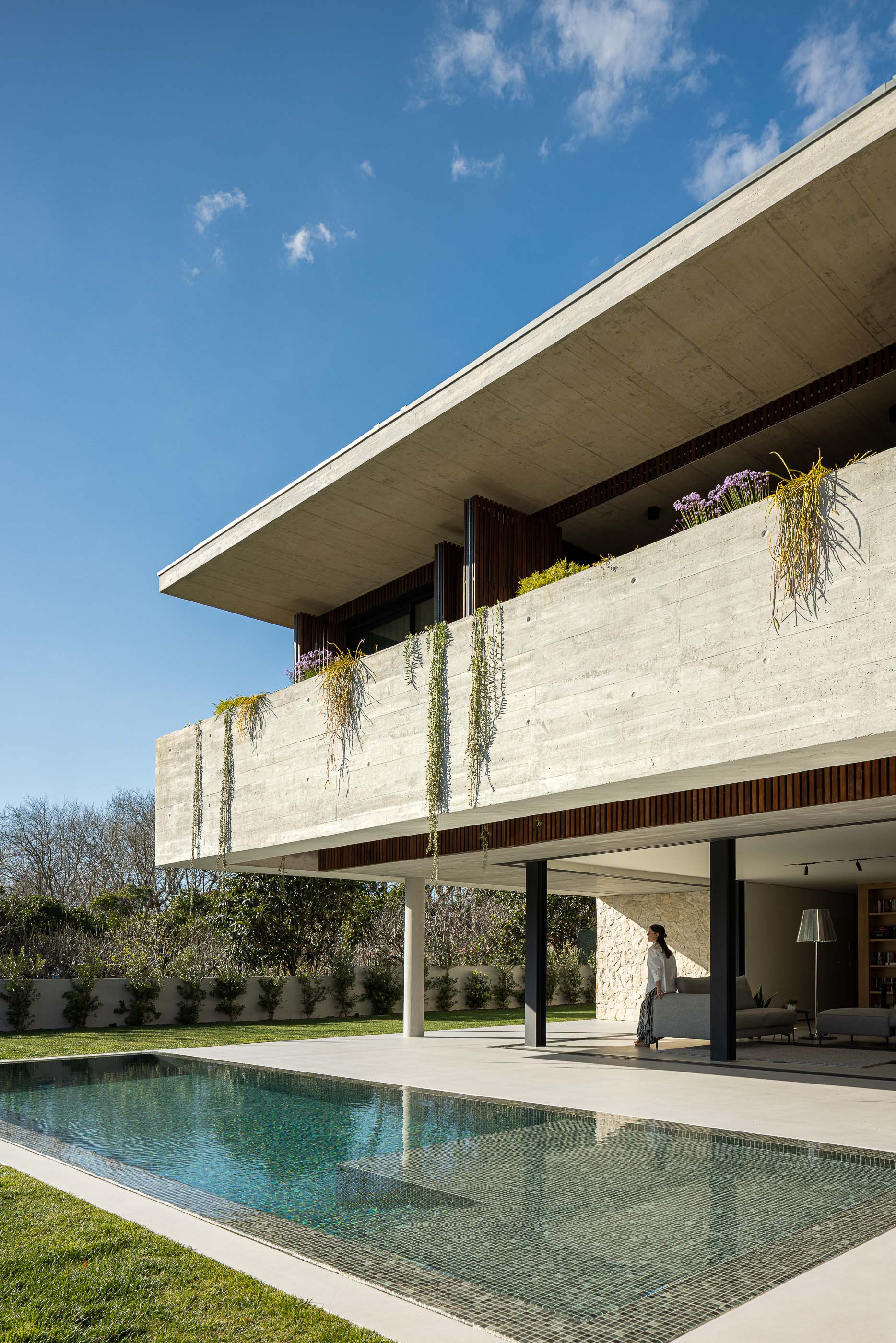 Exterior: Fachada de betão aparente e madeira, com piscina e relvado. — Casa M arquitetura silverline em Vila Nova de Gaia